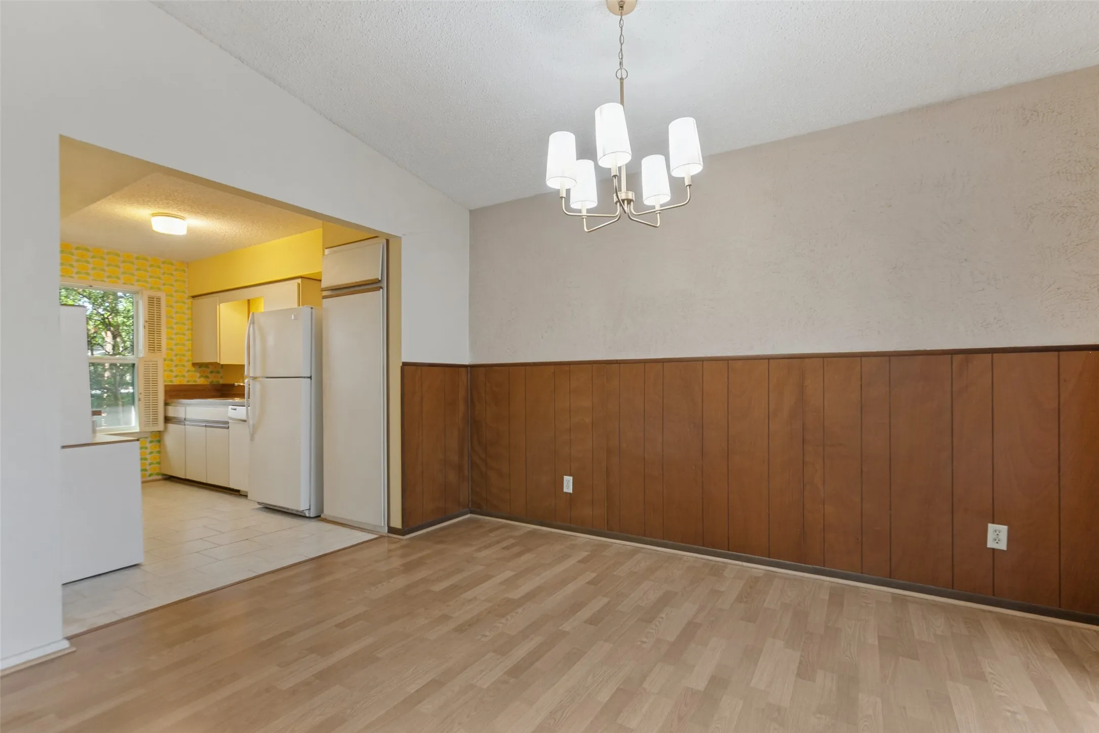 Wood-finish flooring, wood paneling, and an overhead chandelier in the dining area