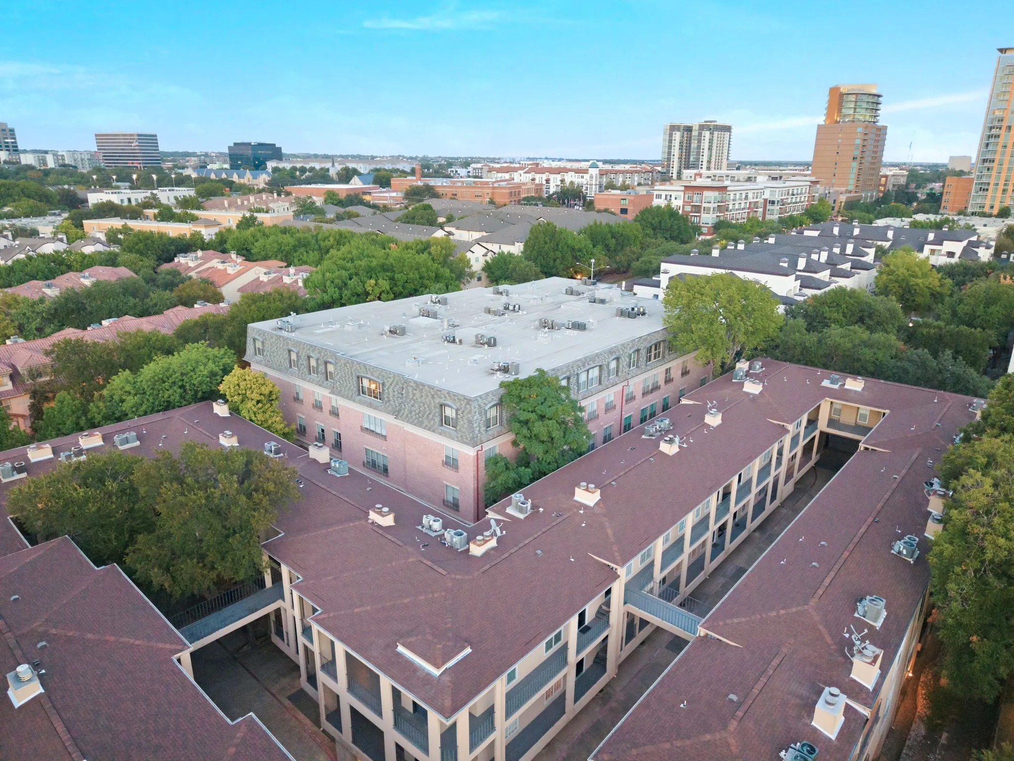 Aerial perspective showcasing multiple buildings with pitched roofs and surrounding mature trees