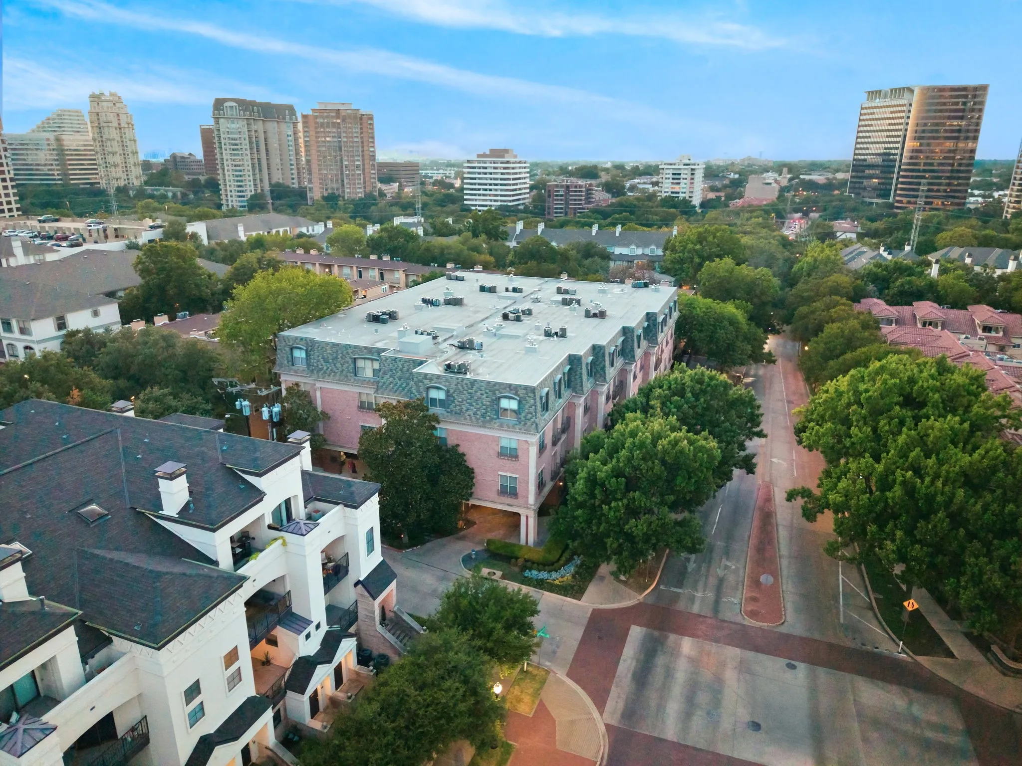 Urban landscape featuring multiple residential buildings, mature trees, and a developed streetscape
