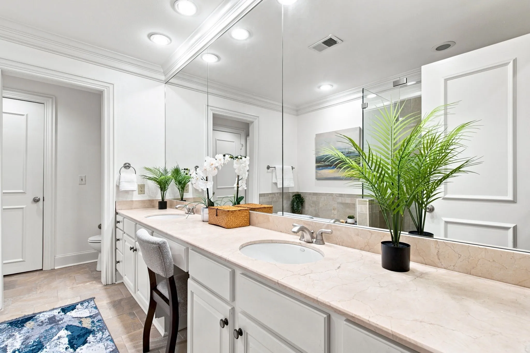 Dual vanity with integrated sinks, light stone countertop, and ample storage cabinetry