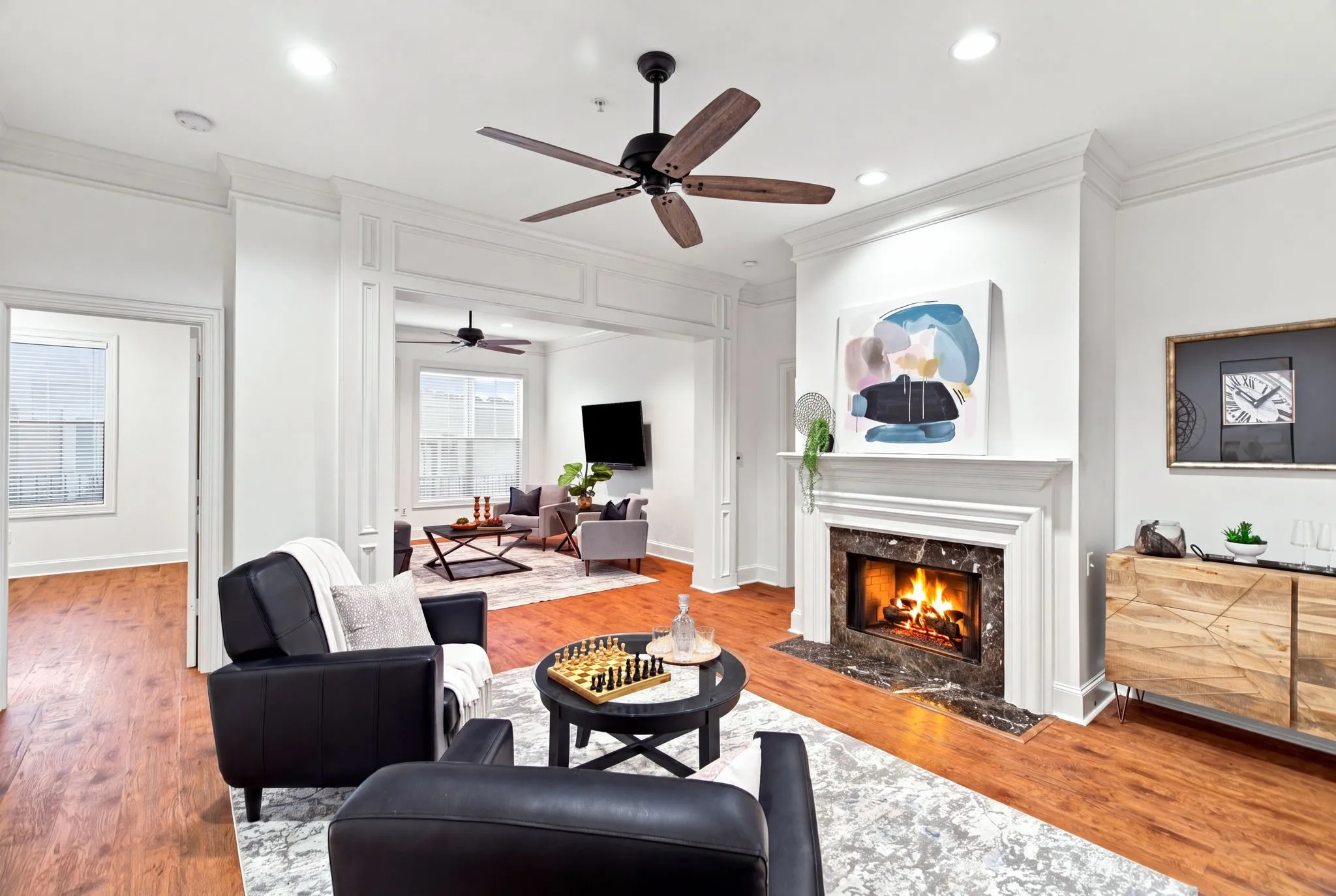 Hardwood-finish flooring, a decorative fireplace with a marble-finish surround, crown molding, a ceiling fan, and recessed lighting
