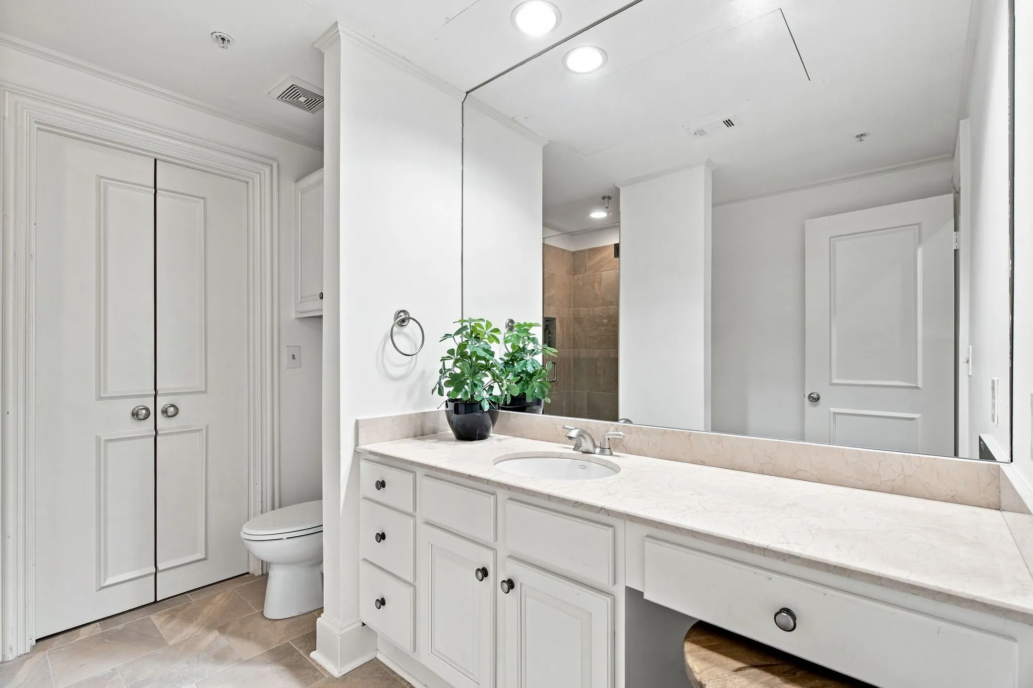Dual-sink vanity with light-toned countertop, built-in cabinetry, and tile flooring