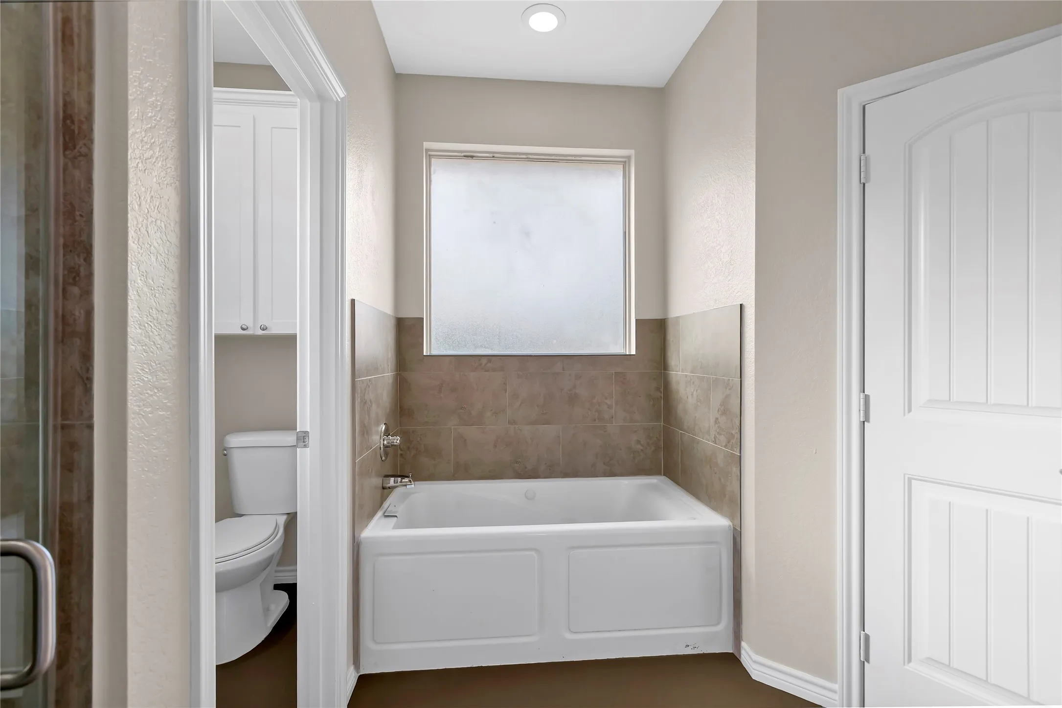 Built-in bathtub with subway tile surround, frosted window, and recessed lighting