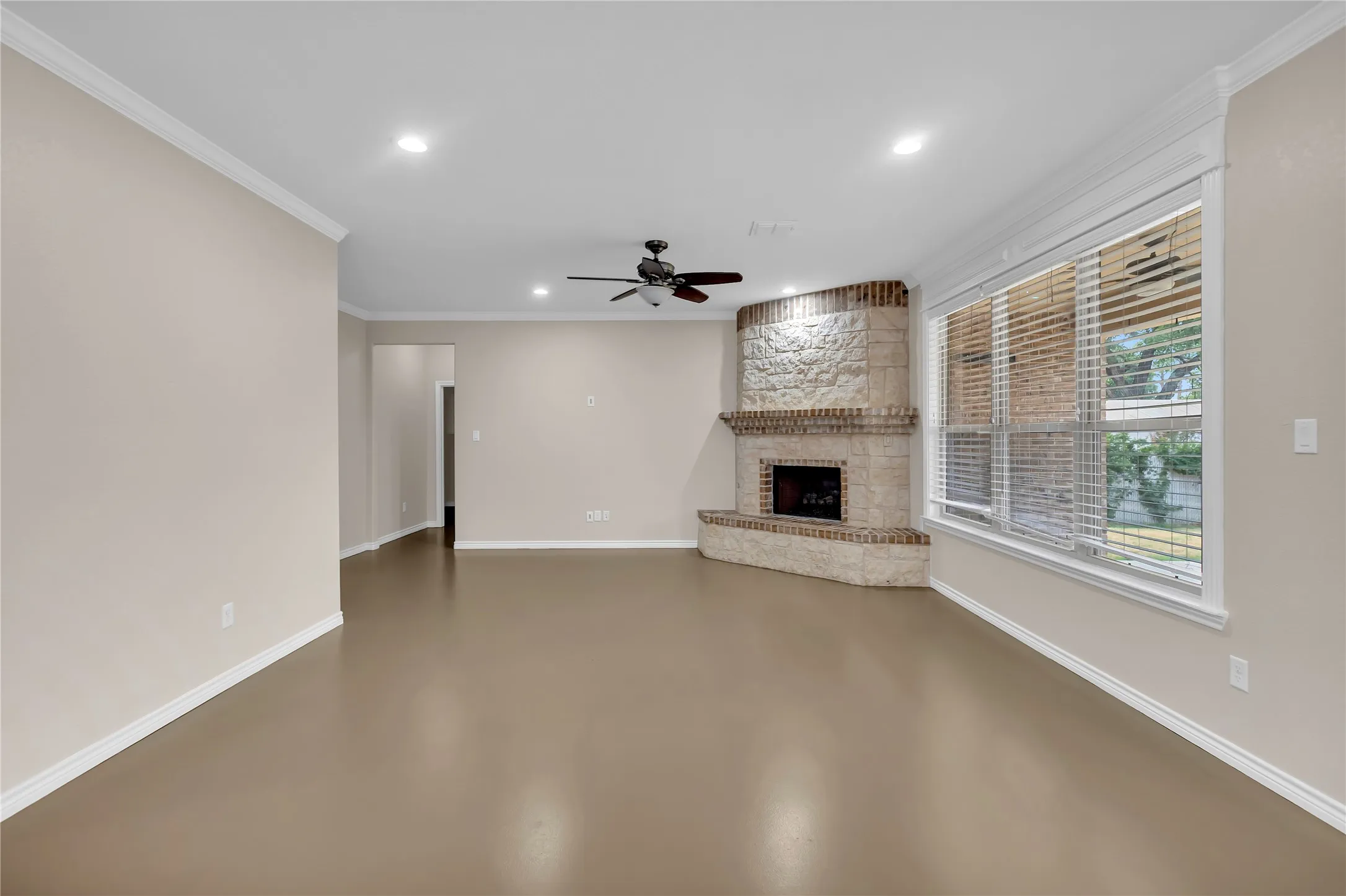 Recessed lighting, crown molding, a corner brick fireplace with stone detailing, a ceiling fan, and large windows with blinds