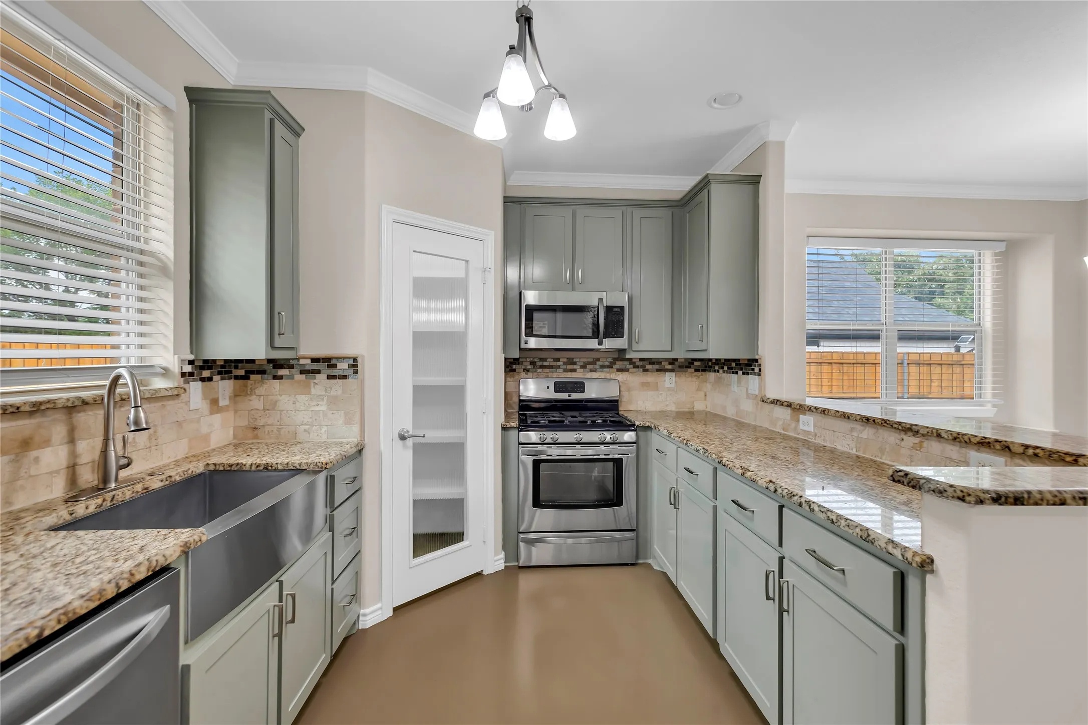 Kitchen featuring gray cabinetry, stainless steel appliances, an apron-front sink, and stone-finish countertops with a tile backsplash