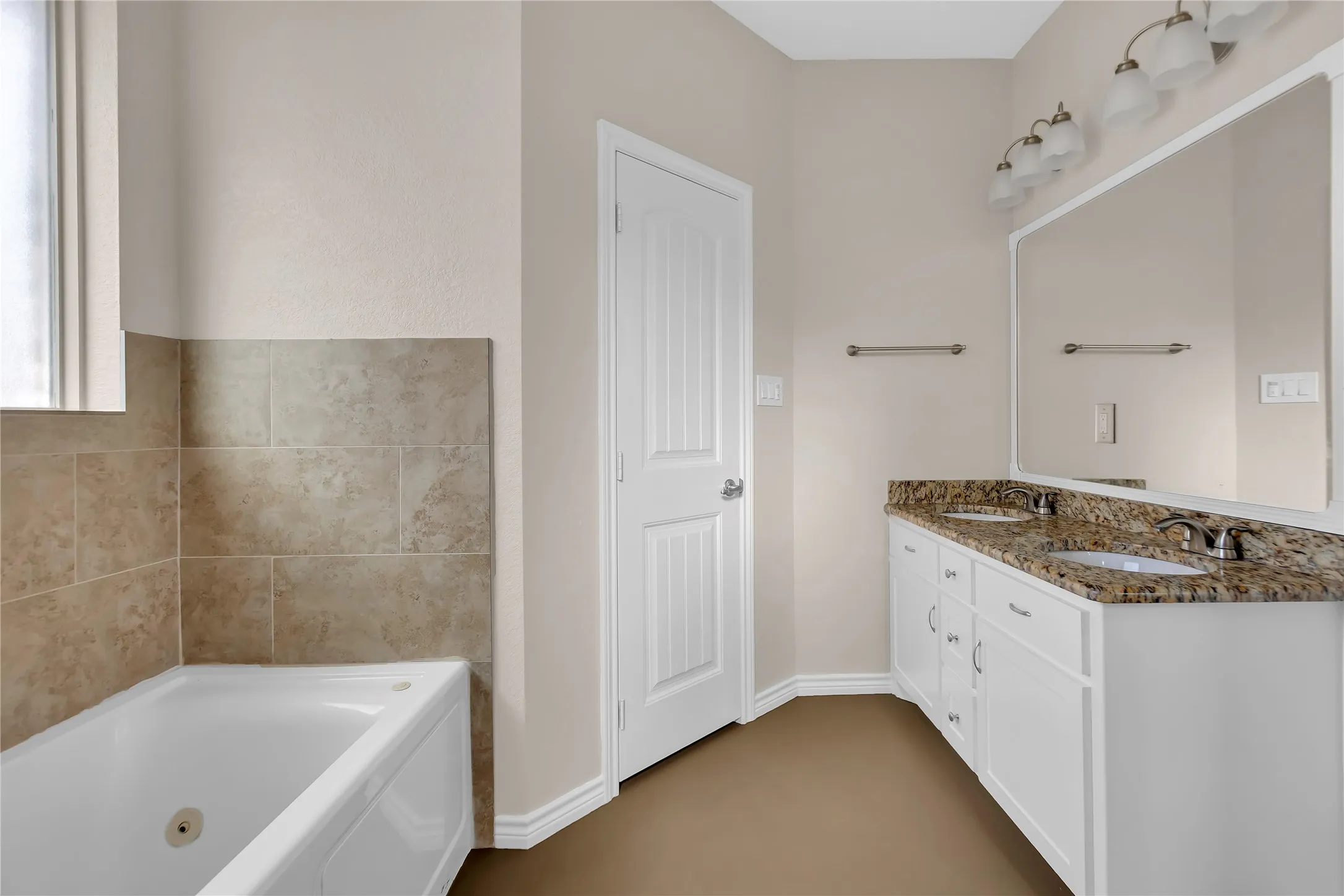 Dual vanity with granite countertop, white cabinetry, and undermount sinks