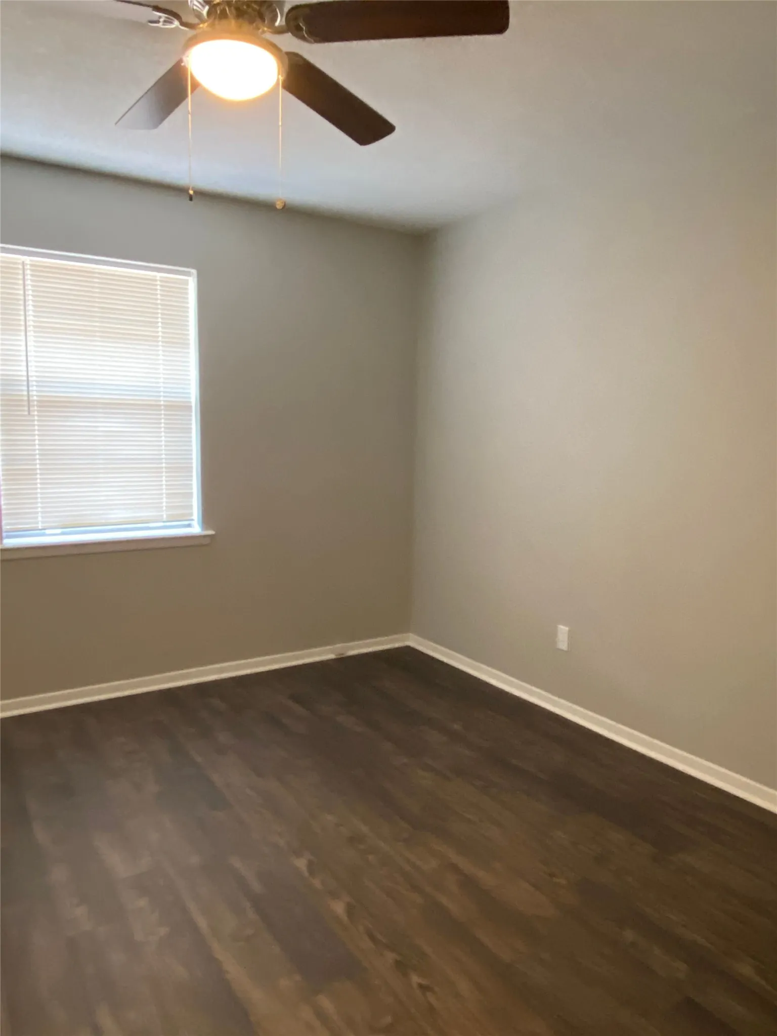 Ceiling fan with light fixture, wood-finish flooring, neutral wall paint, and window with blinds