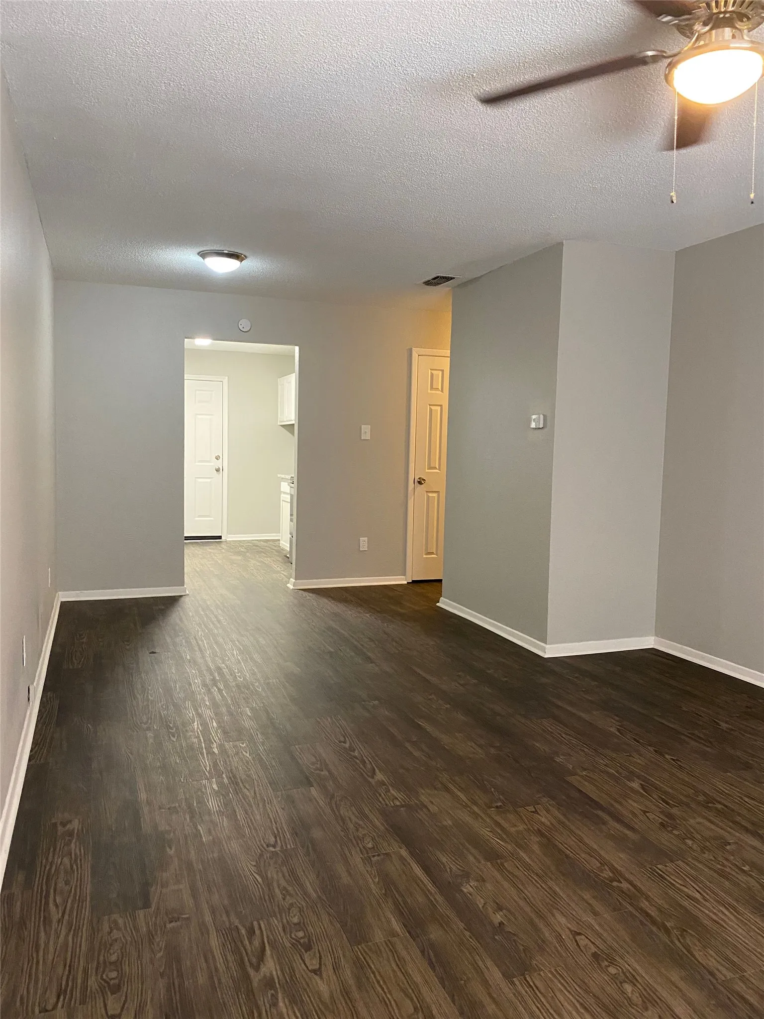 Wood-finish flooring throughout, light gray wall paint, and a ceiling fan with integrated lighting