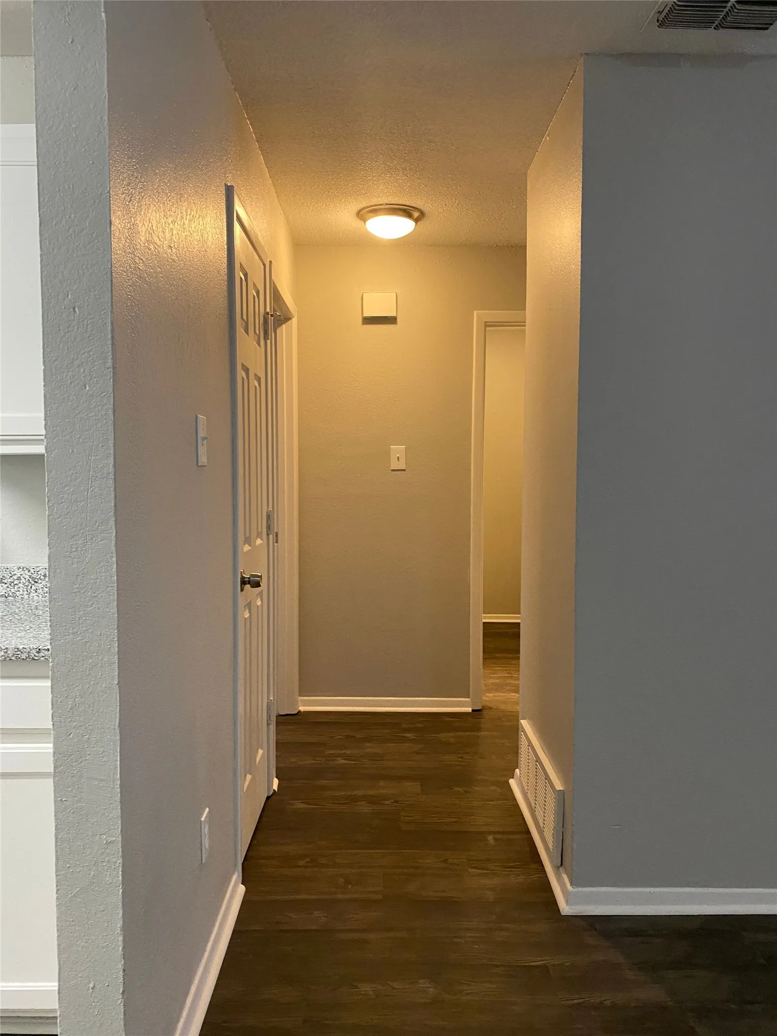 Hallway with wood-finish flooring, light gray wall paint, and white trim