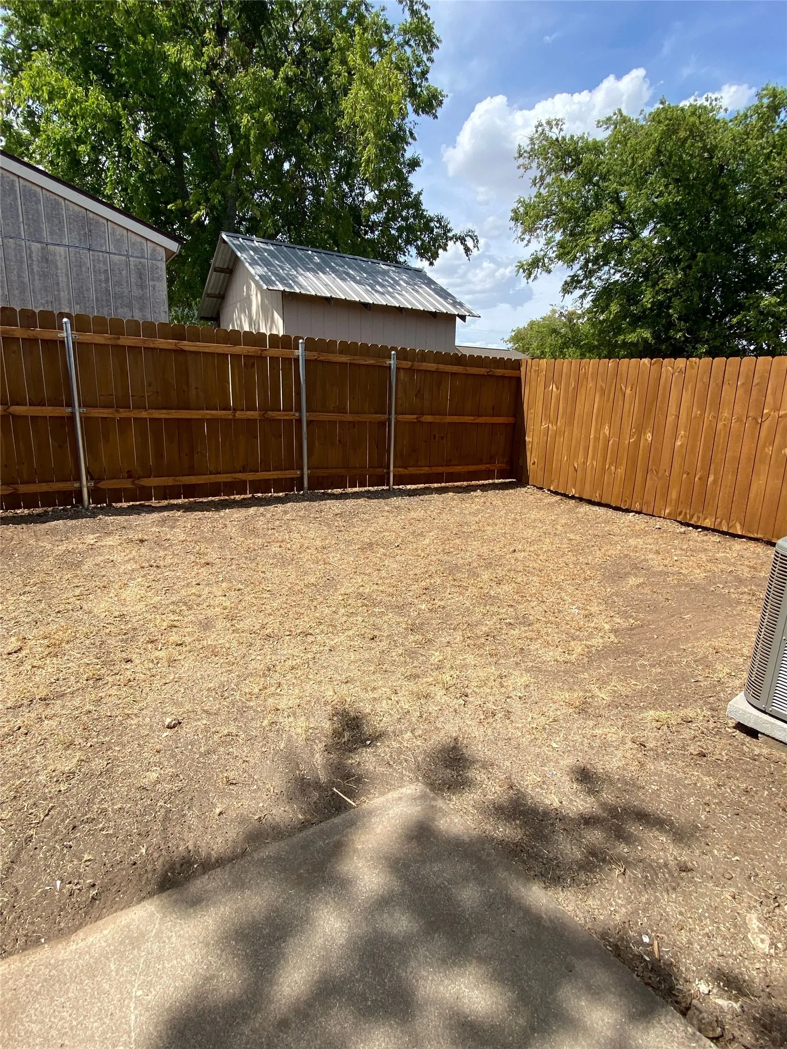 Backyard area featuring a wood privacy fence and a concrete pad