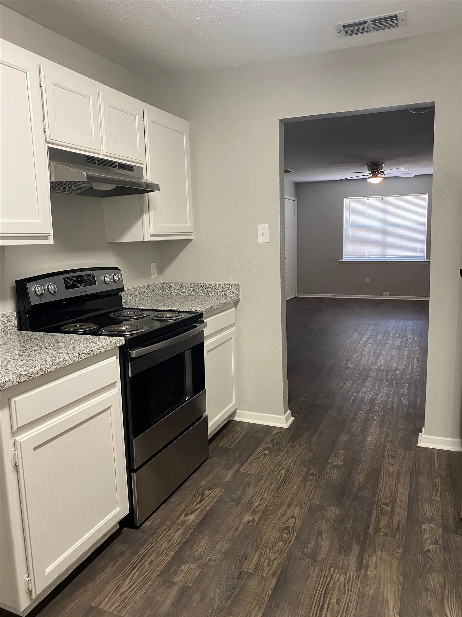 Kitchen featuring white cabinetry, speckled countertops, stainless steel electric range, and wood-finish flooring