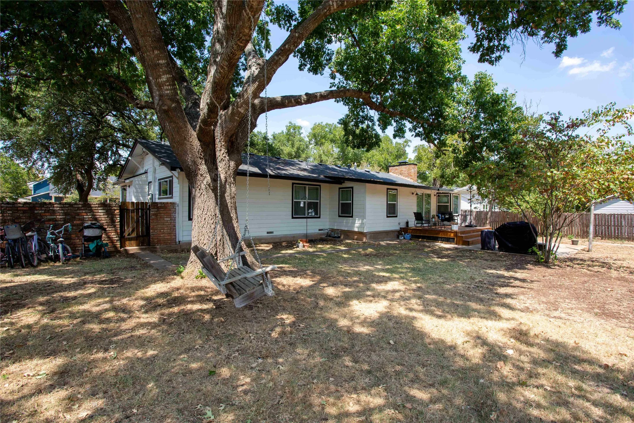 Expansive rear yard featuring mature climbing trees, a wood deck, and a wood privacy fence