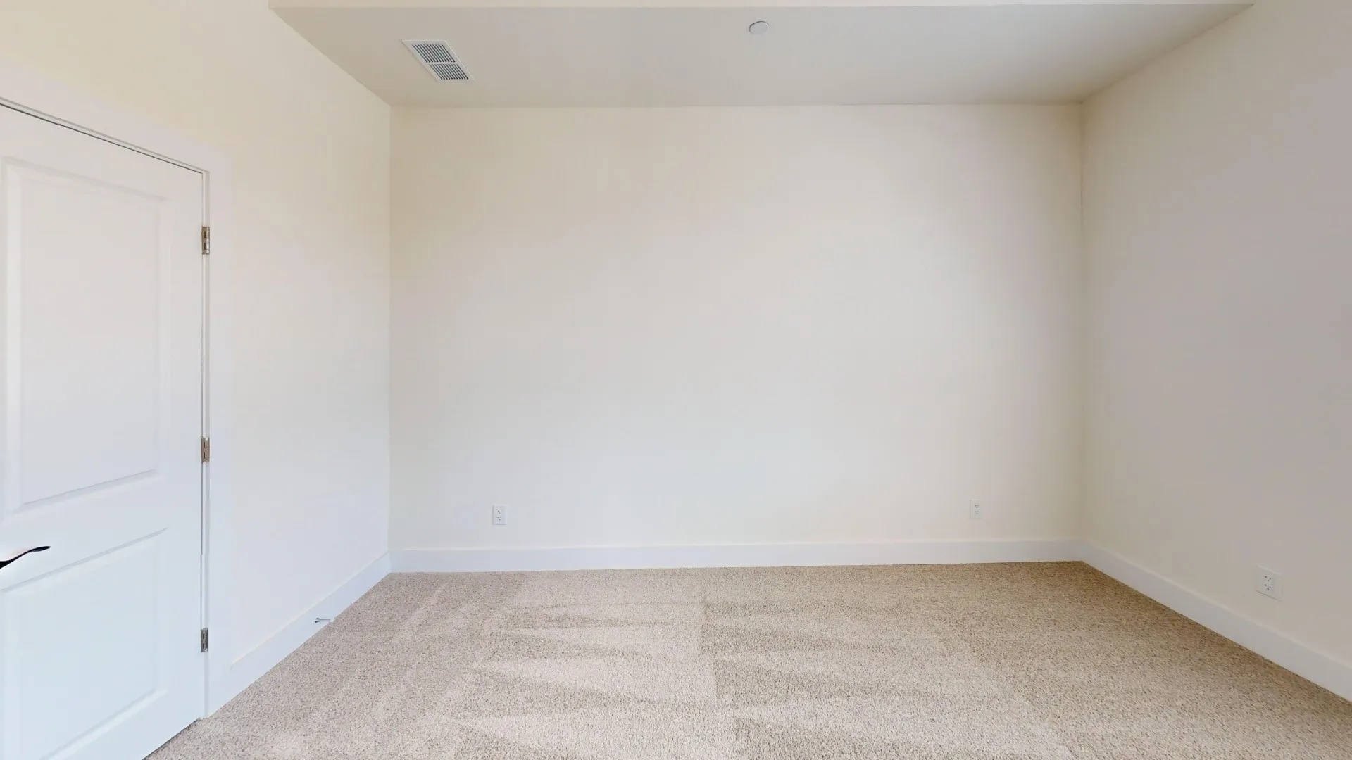 Neutral-toned carpeting, white trim, and a white interior door with a black handle