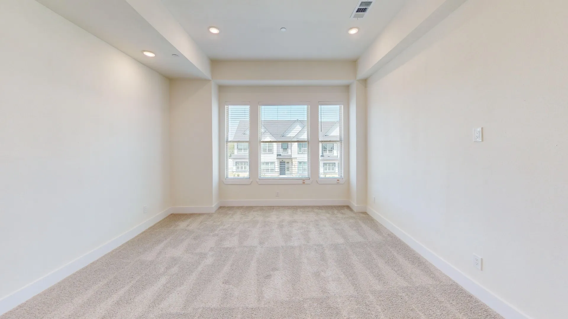 Recessed lighting, light-toned carpeting, bay window, white window blinds, and neutral wall paint