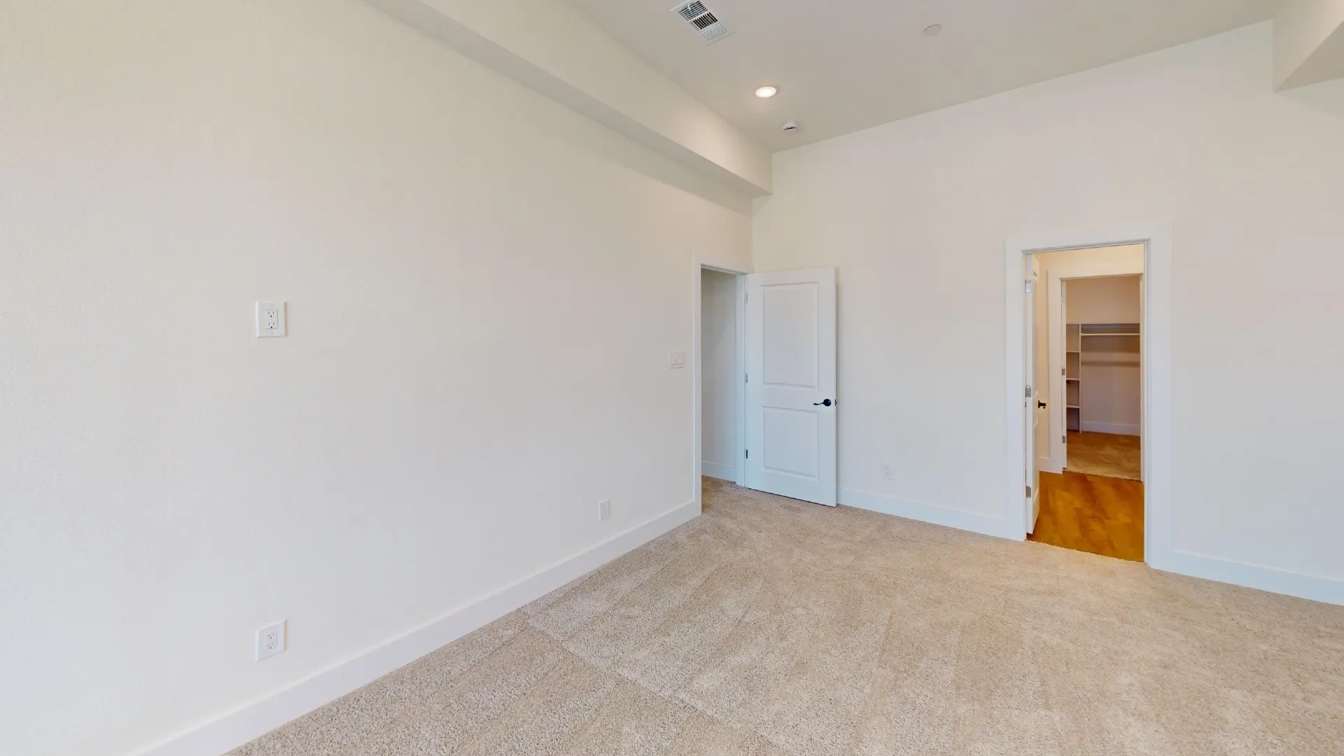 Carpeted room with white walls, recessed lighting, and two white panel doors