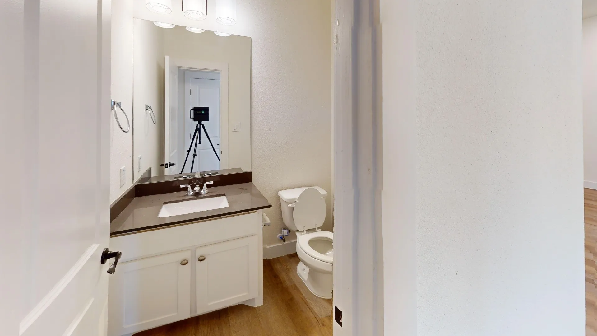 White vanity with shaker-style cabinetry, dark countertop, rectangular undermount sink, and chrome faucet