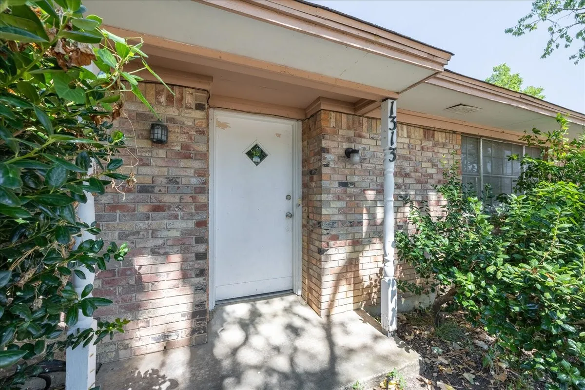 Brick exterior, entry door with diamond-shaped window, covered porch, exterior lighting, window with multiple panes
