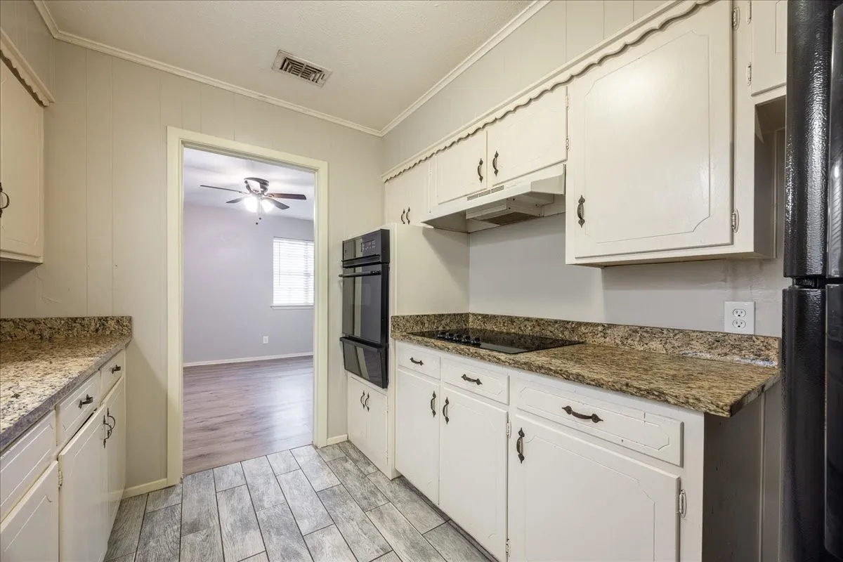 Kitchen featuring white cabinetry, stone-finish countertops, a built-in double oven, and a ceramic cooktop
