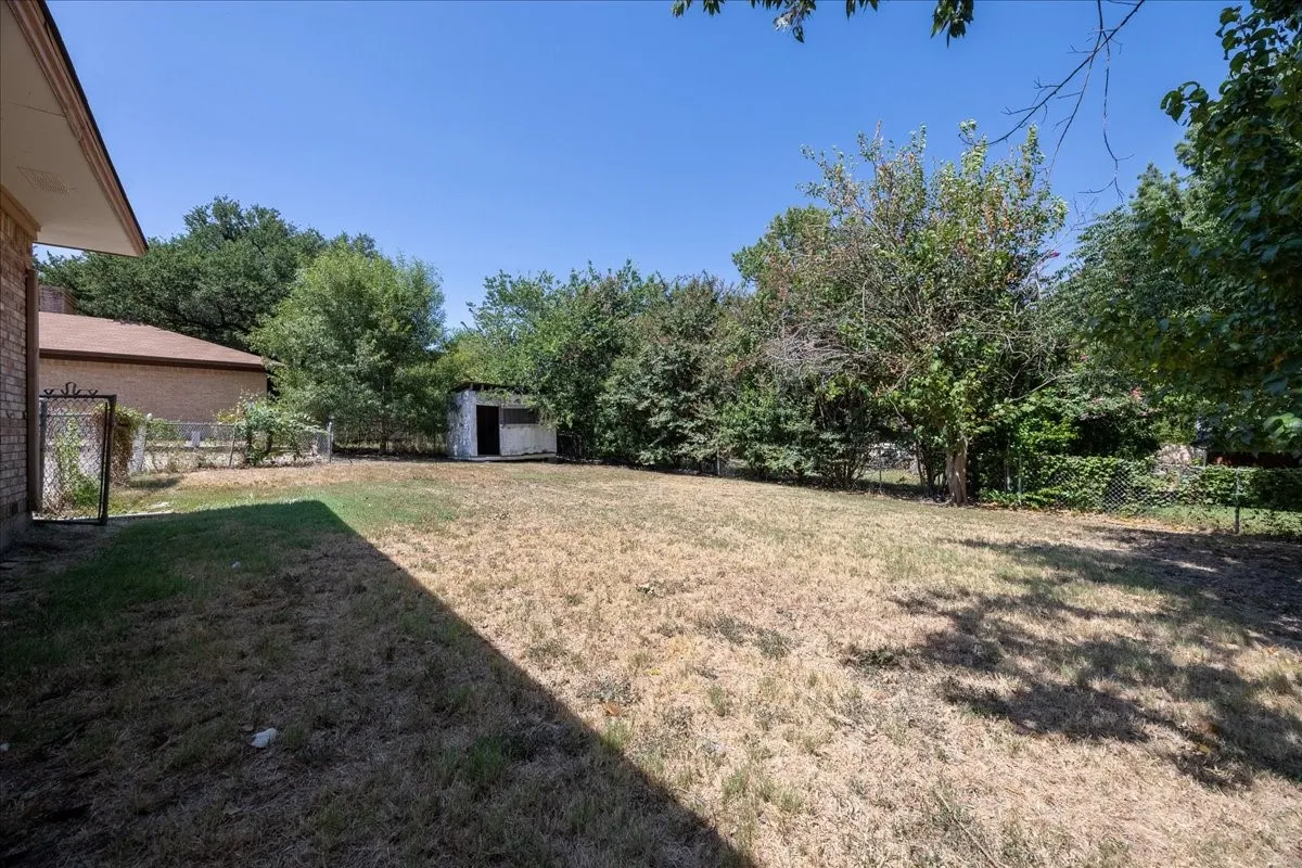 Expansive outdoor space featuring a detached storage shed and mature perimeter trees