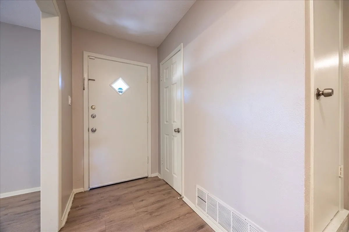 Entryway featuring wood-finish flooring, a white entry door with a decorative window, and light-toned walls