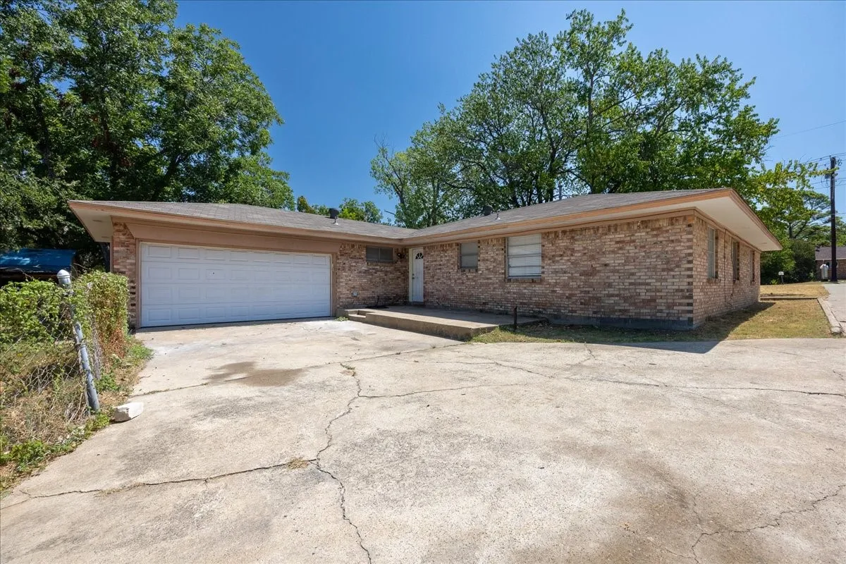 Brick exterior featuring a two-car garage and concrete driveway