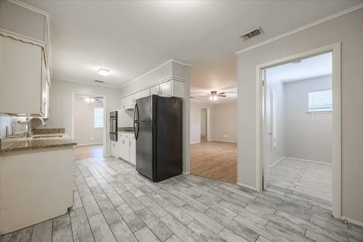 Kitchen featuring wood-look tile flooring, white cabinetry, integrated double wall ovens, and granite-style countertops