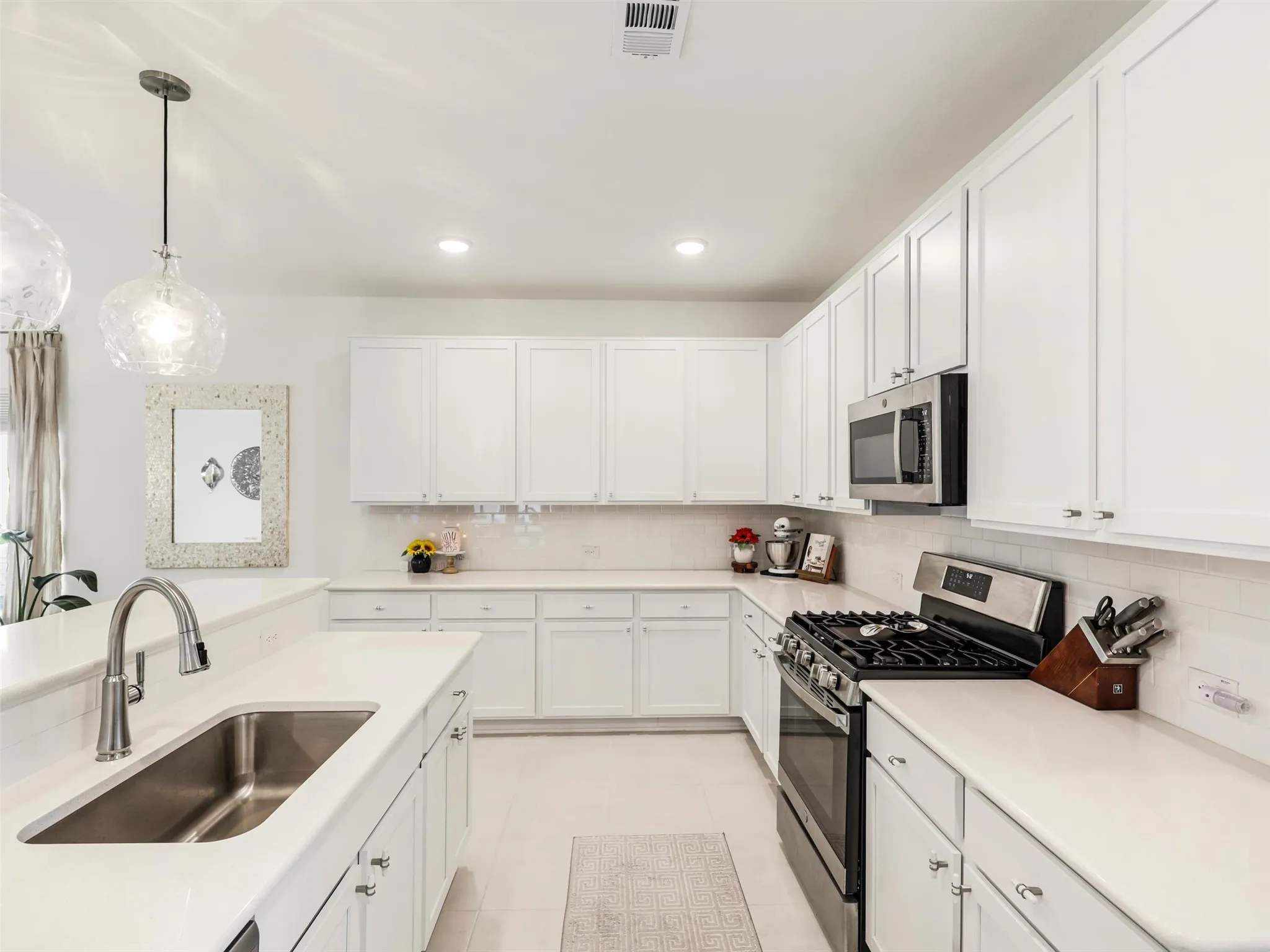 Well-appointed kitchen featuring abundant white cabinetry, stainless steel appliances, a gas range, and a large single-basin sink