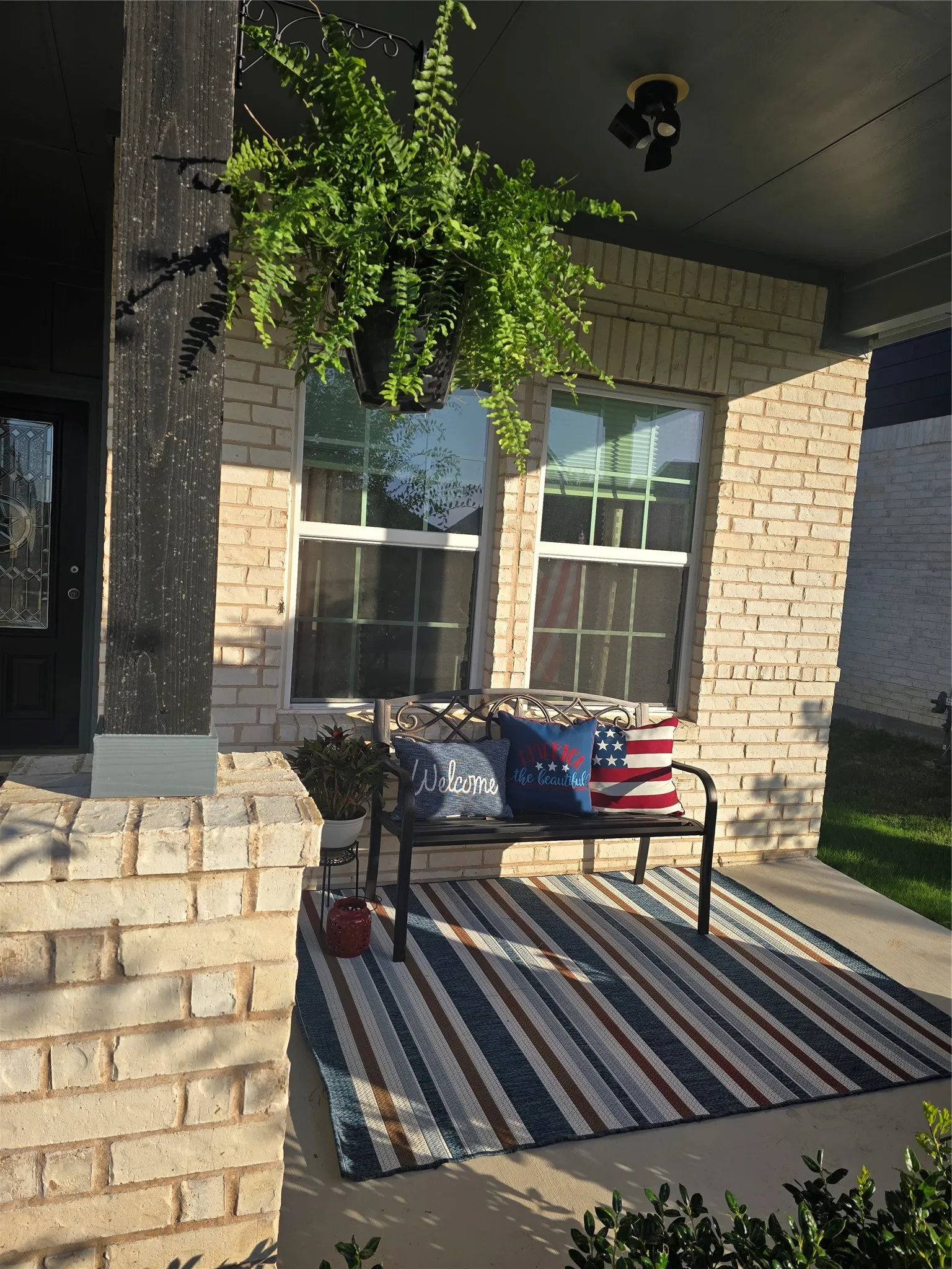 Entry porch featuring light brick exterior, a decorative glass-paneled entry door, and a black track lighting fixture