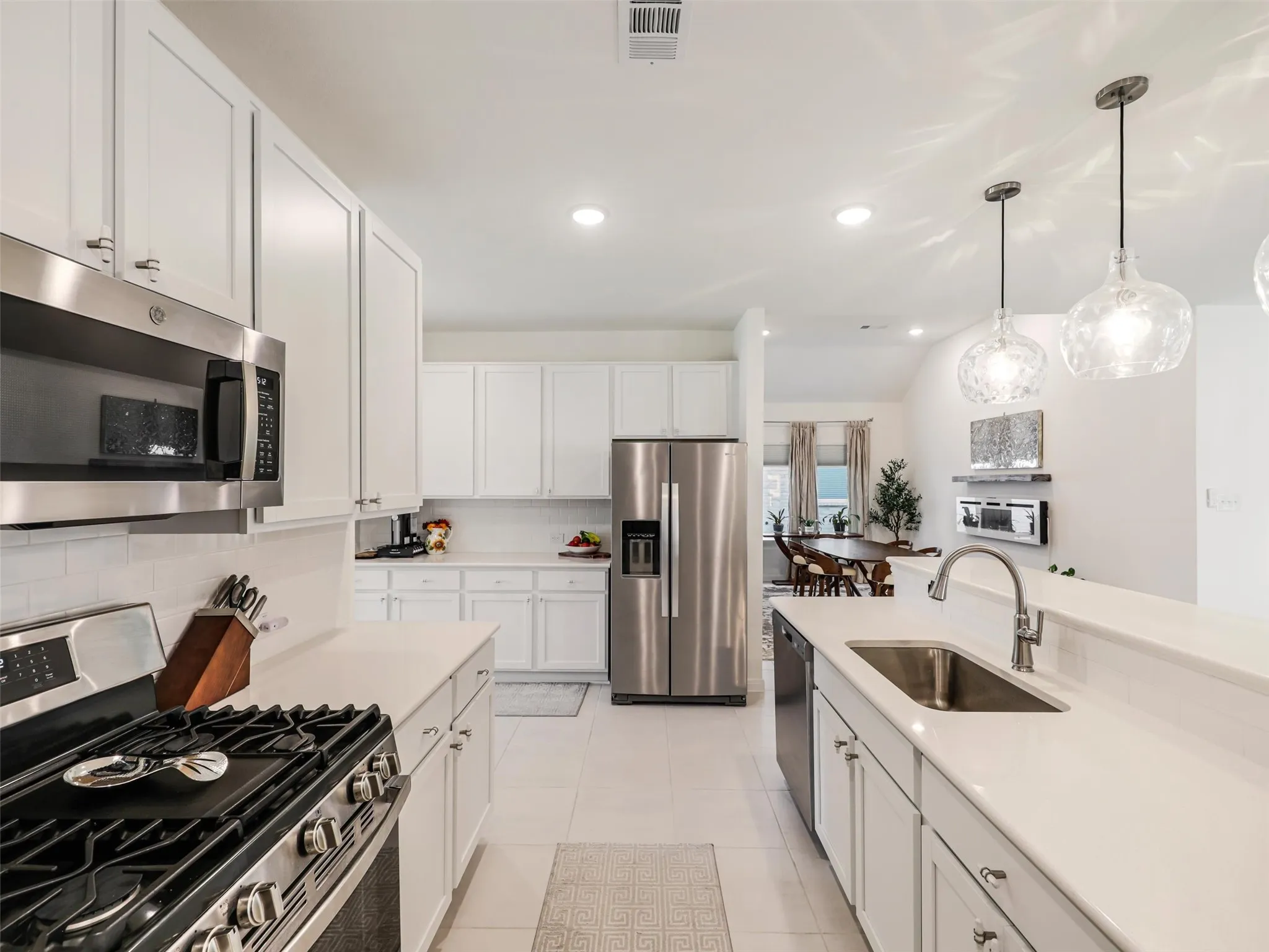 Kitchen featuring extensive white cabinetry, stainless steel appliances, light countertops, and a subway tile backsplash