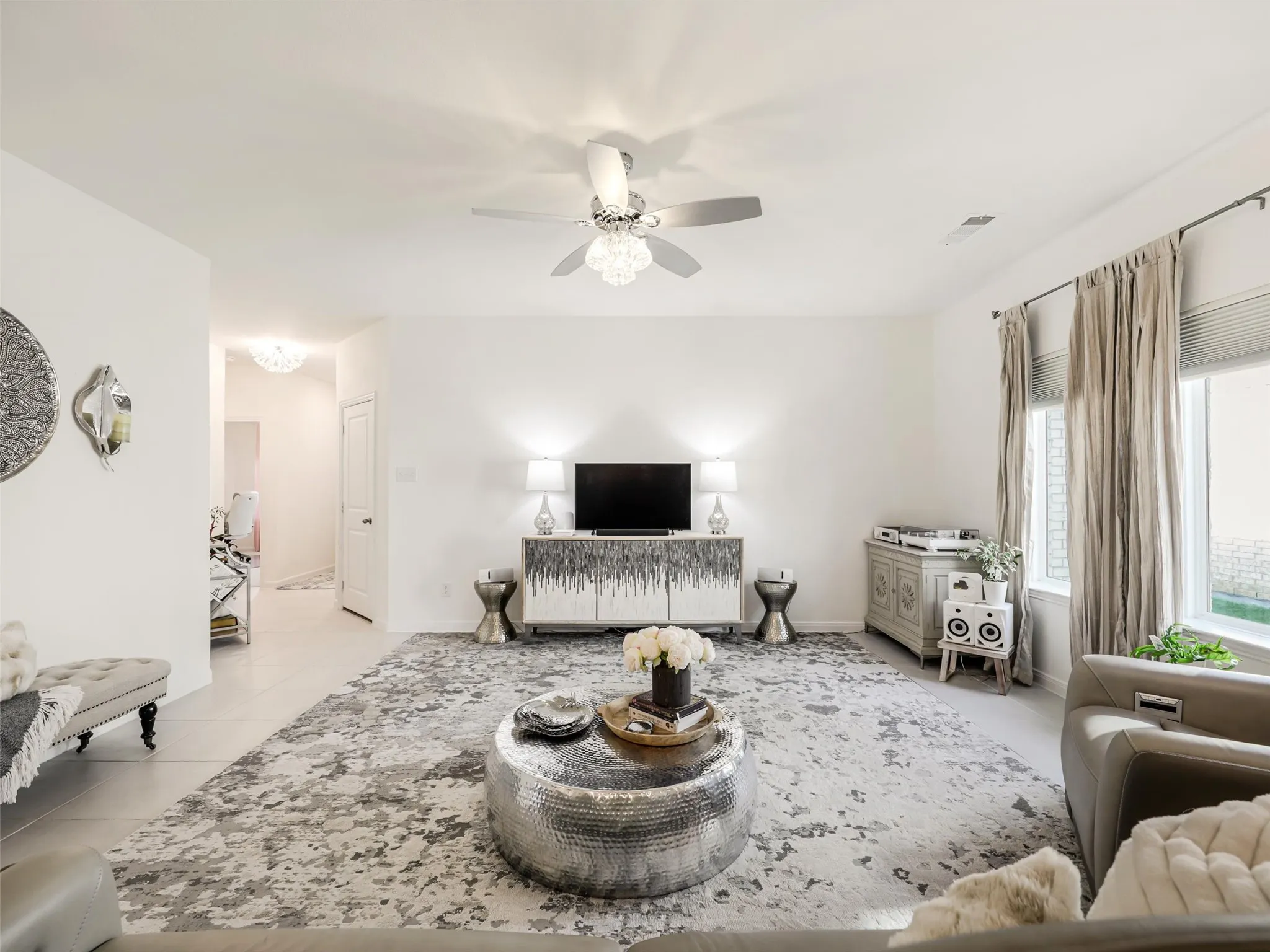 Recessed lighting, ceiling fan with chandelier, and large window provide ample illumination