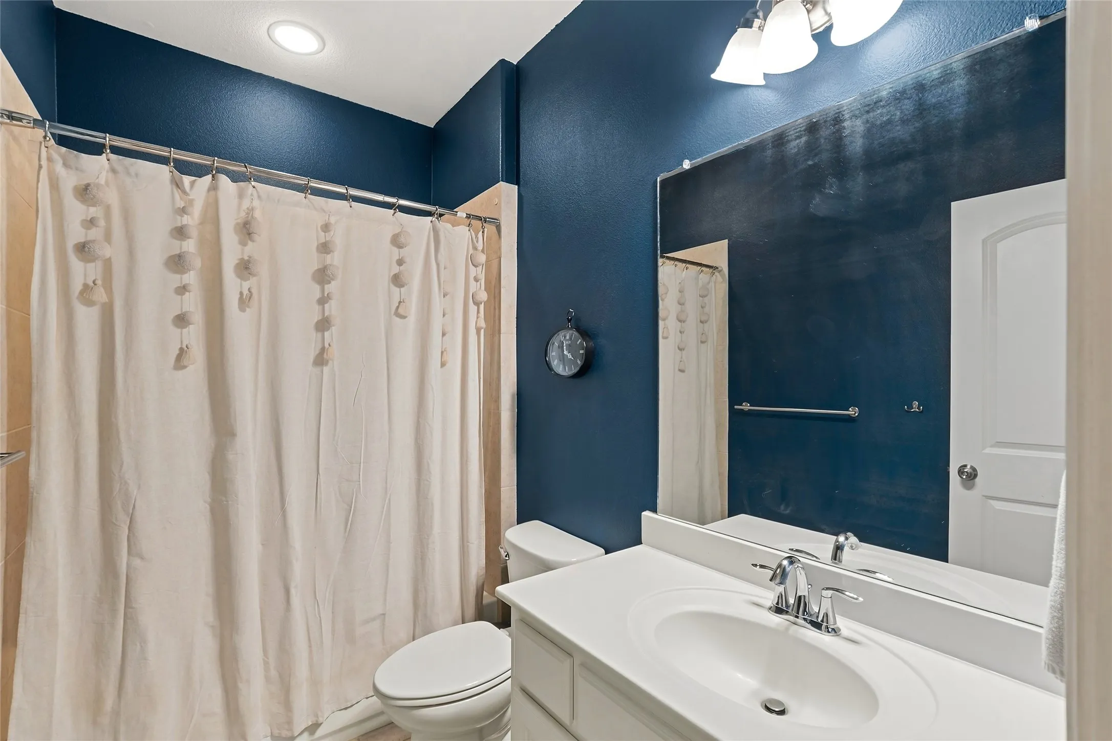 Vanity with integrated sink, chrome faucet, and expansive wall mirror