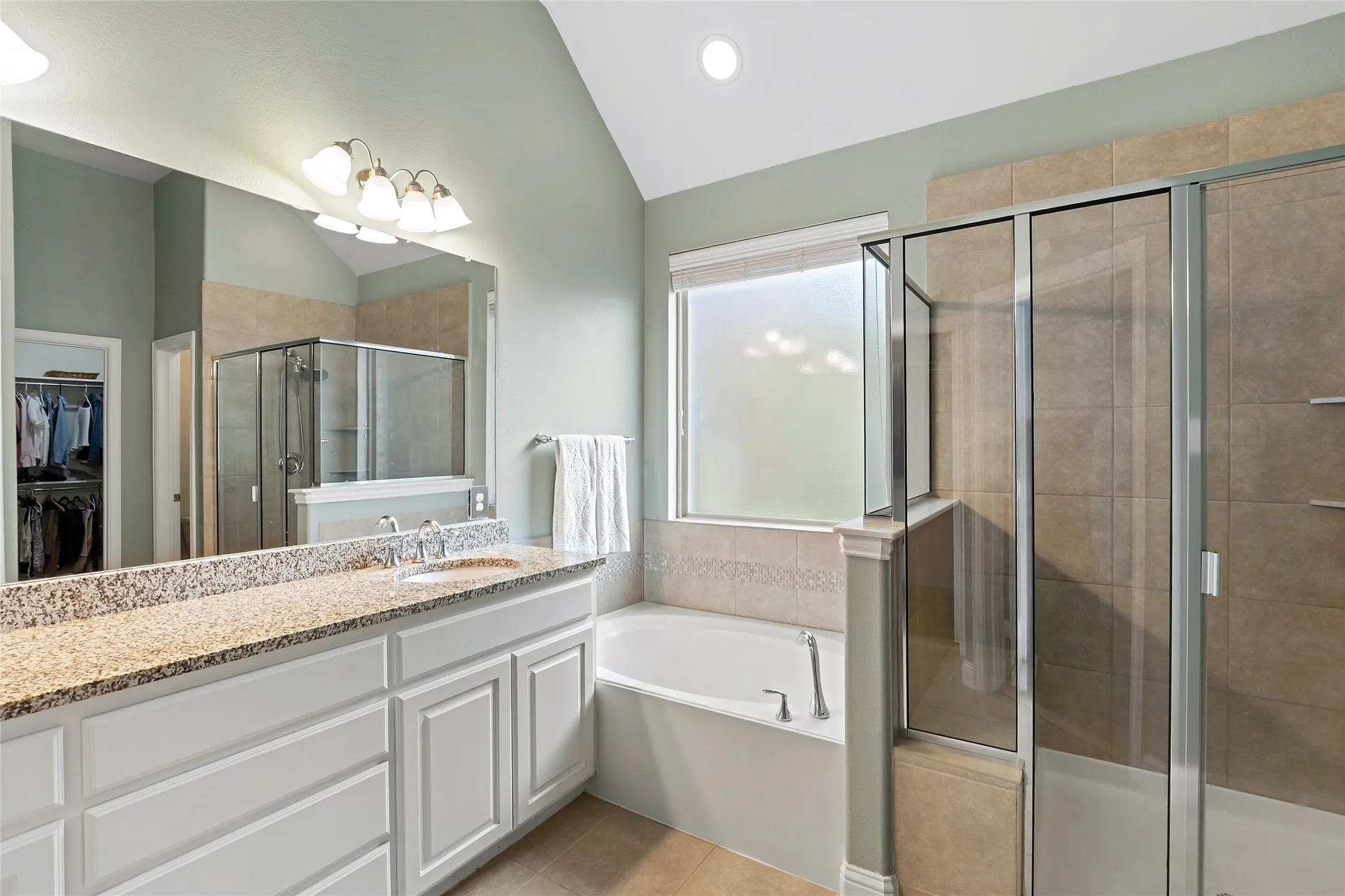 Double vanity with a speckled countertop and integrated sink, framed by a large mirror