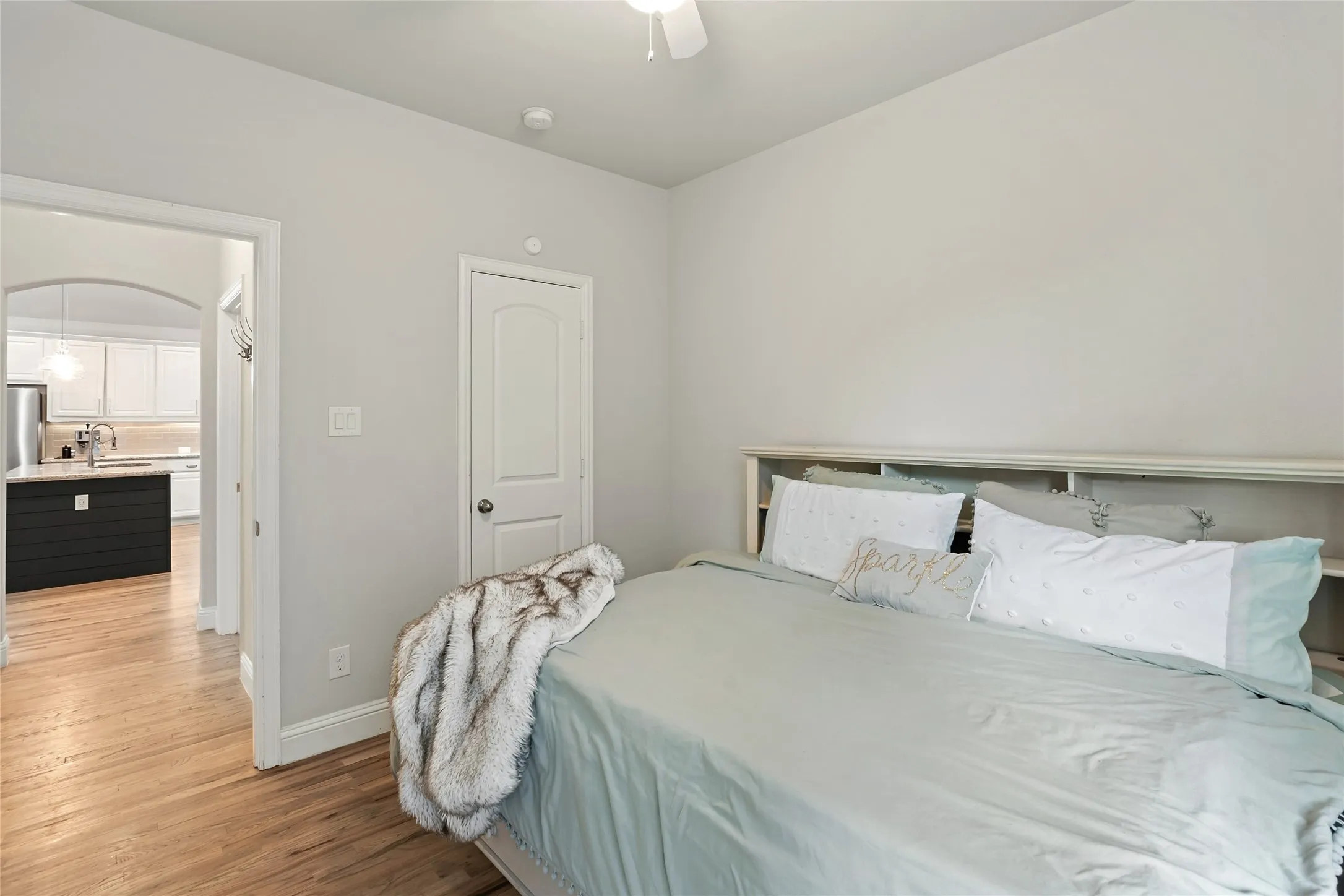 Hardwood-finish flooring, built-in shelving, arched doorway, recessed lighting, and a ceiling fan