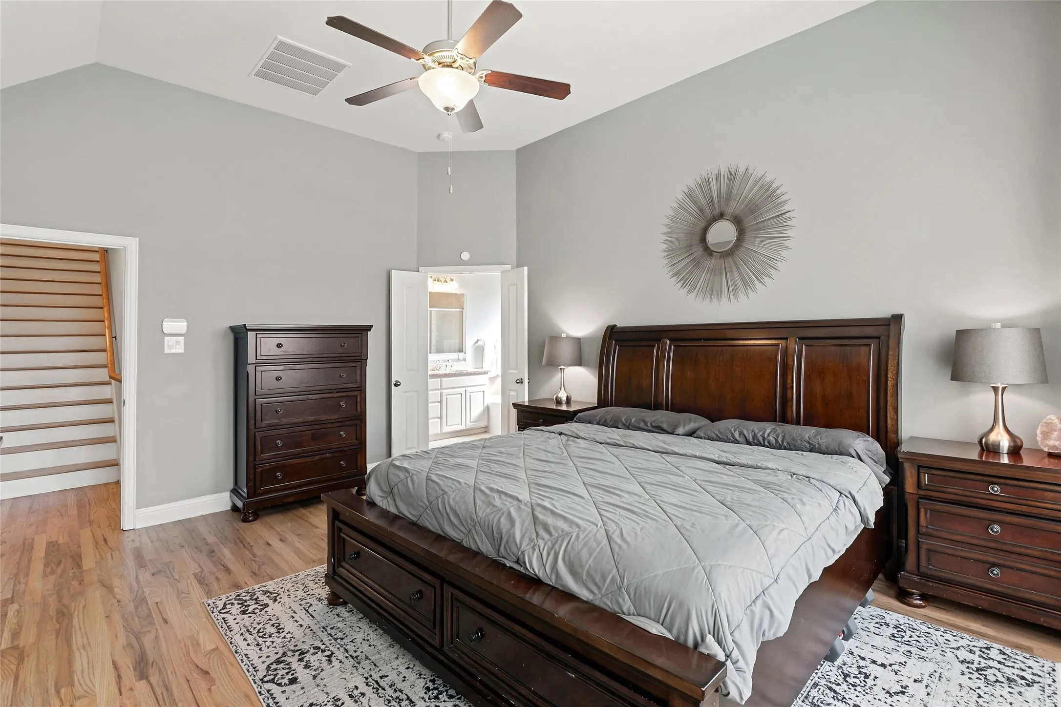 Wood-finish flooring throughout, vaulted ceiling with a ceiling fan, and light gray wall paint