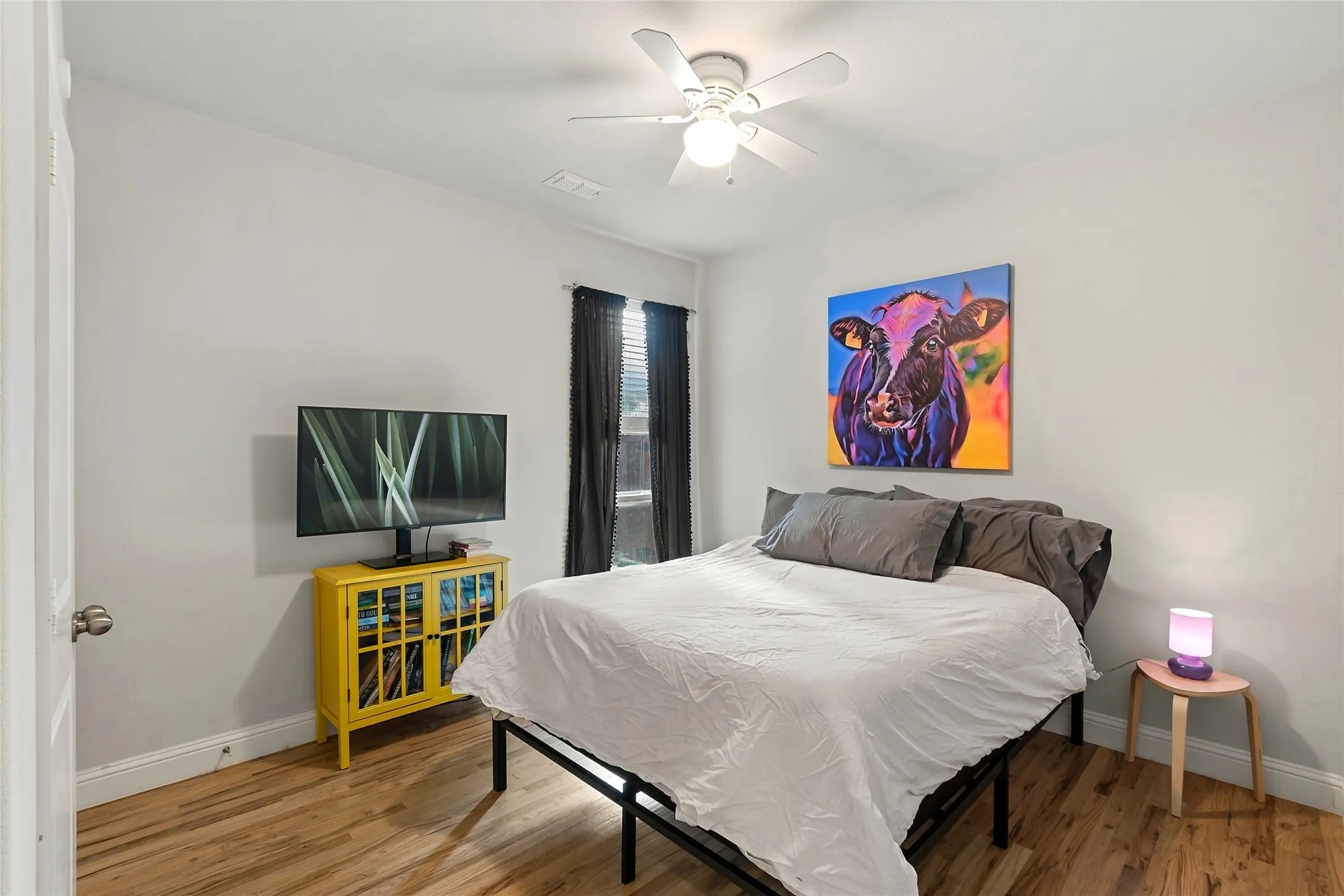 Wood-finish flooring throughout, bright white walls, and a ceiling fan with integrated lighting