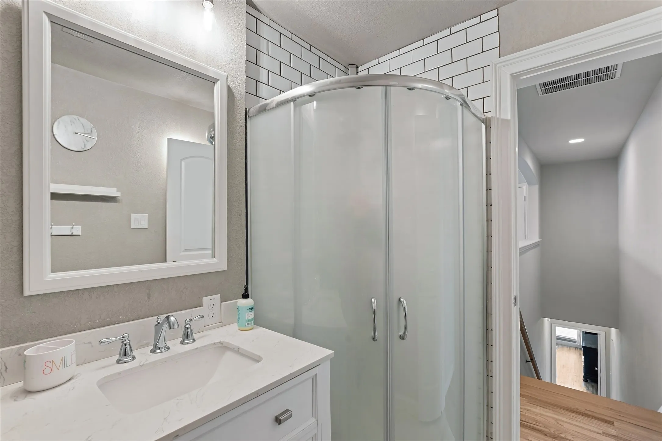 White vanity with a single basin sink, chrome faucet, and framed mirror