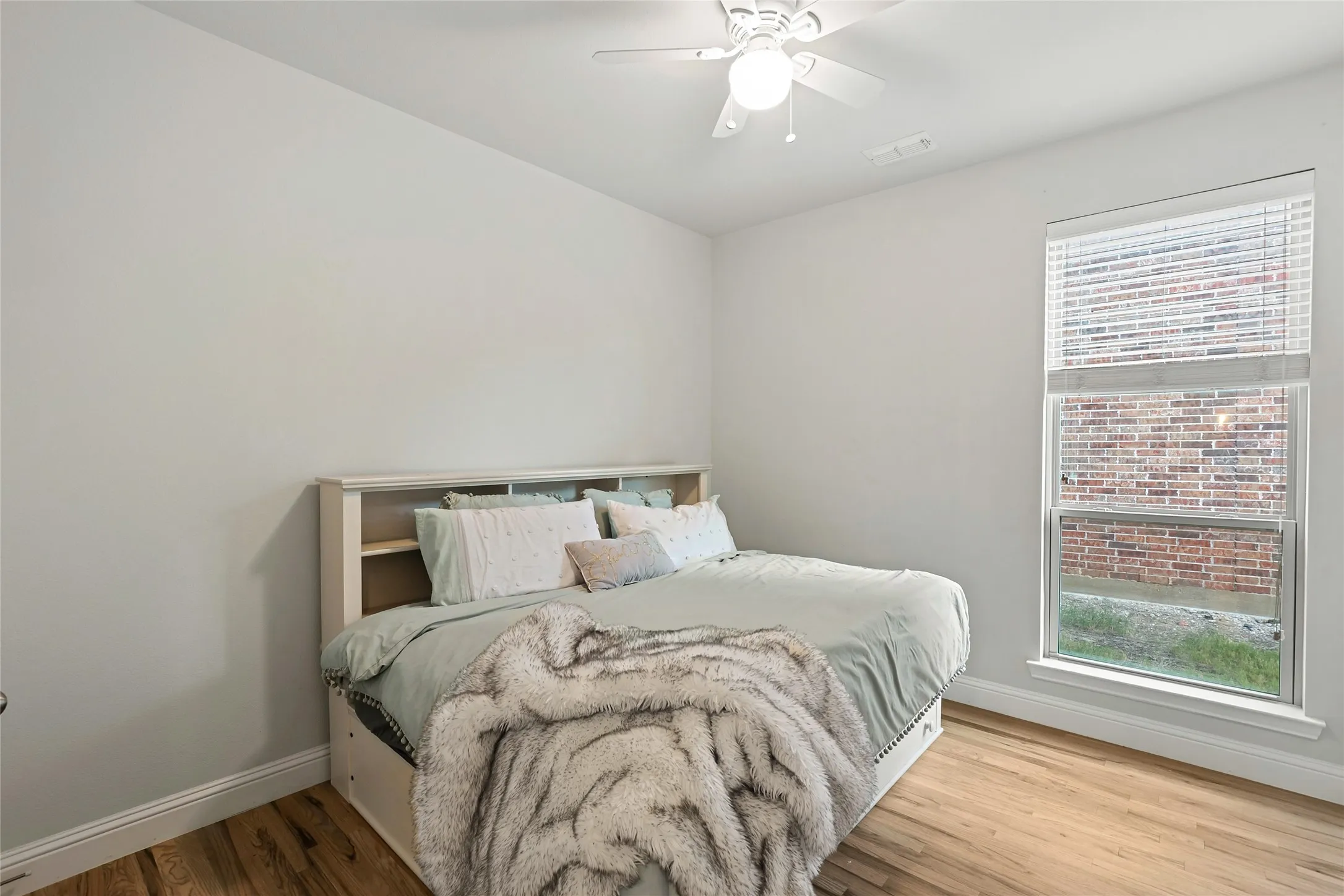 Neutral wall color, wood-finish flooring, white ceiling fan, large window with blinds, and white trim