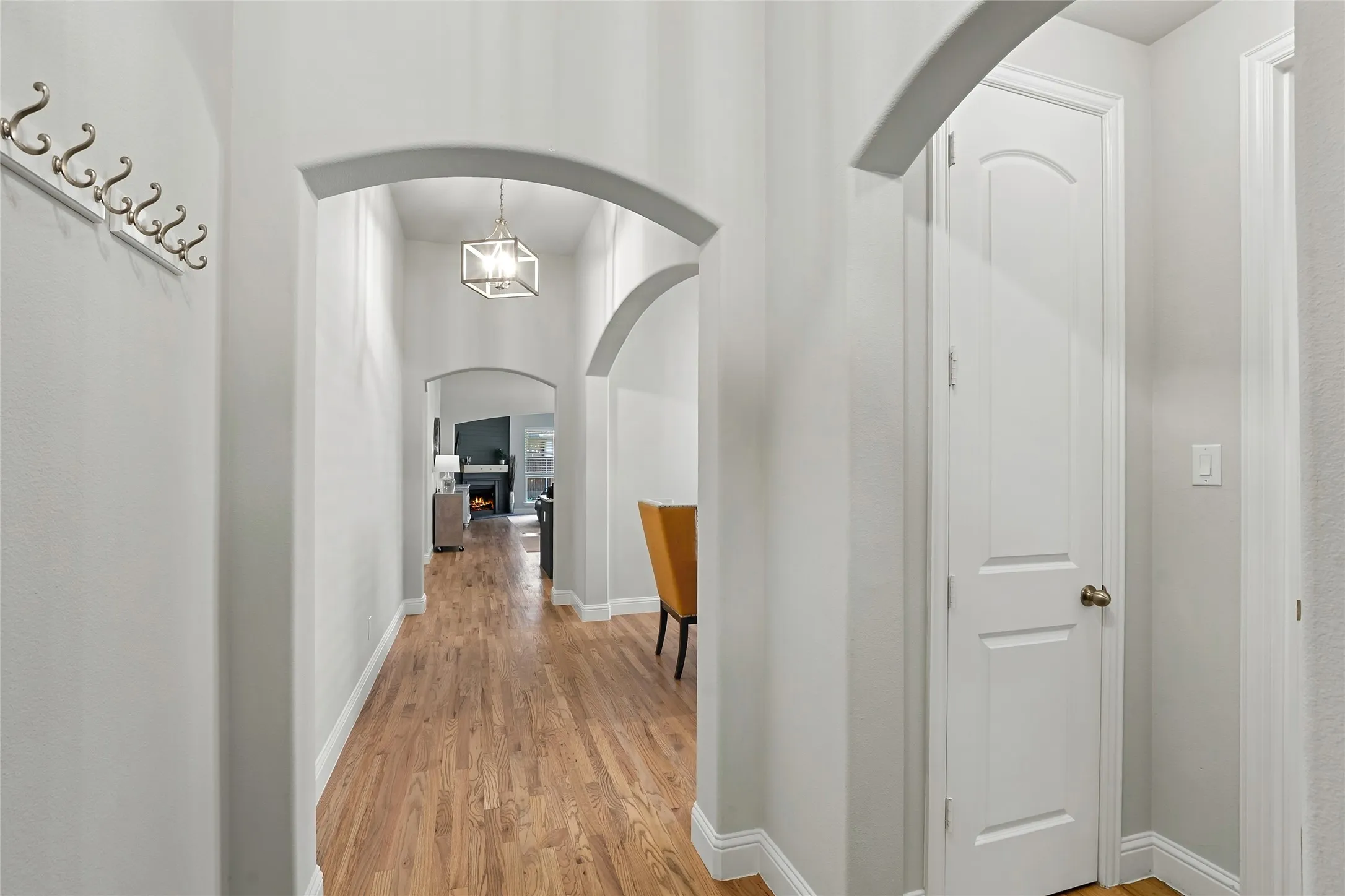 Hallway featuring arched doorways, wood-finish flooring, a contemporary ceiling fixture, and a paneled interior door