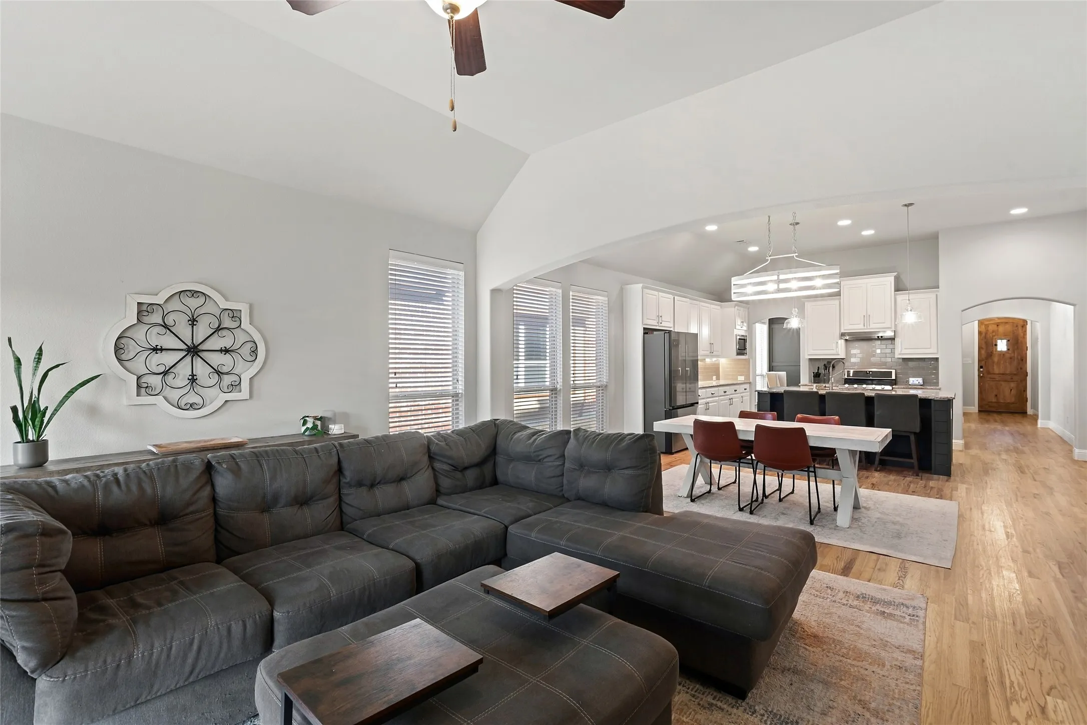 Vaulted ceilings, wood-finish flooring, recessed lighting, and a kitchen island with built-in seating
