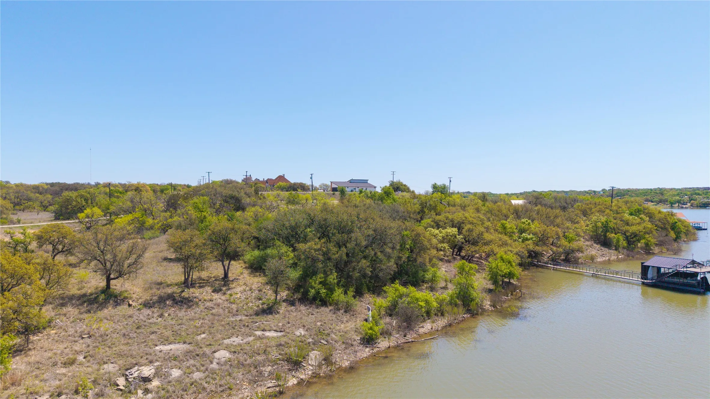 Waterfront property featuring a private boat dock, lush green trees, and natural landscaping