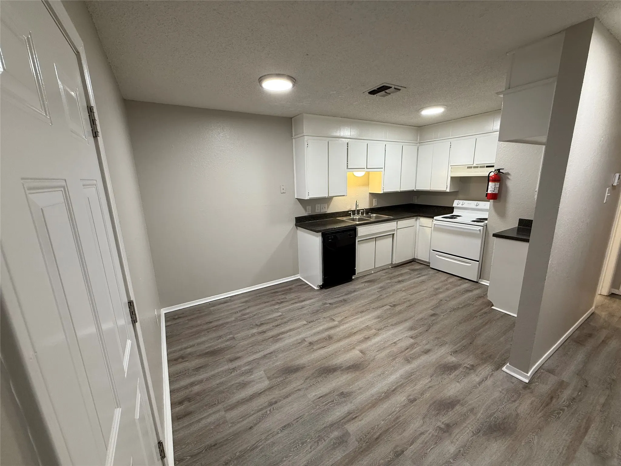 Full kitchen featuring white cabinetry, dark countertops, a white electric range, and wood-finish flooring