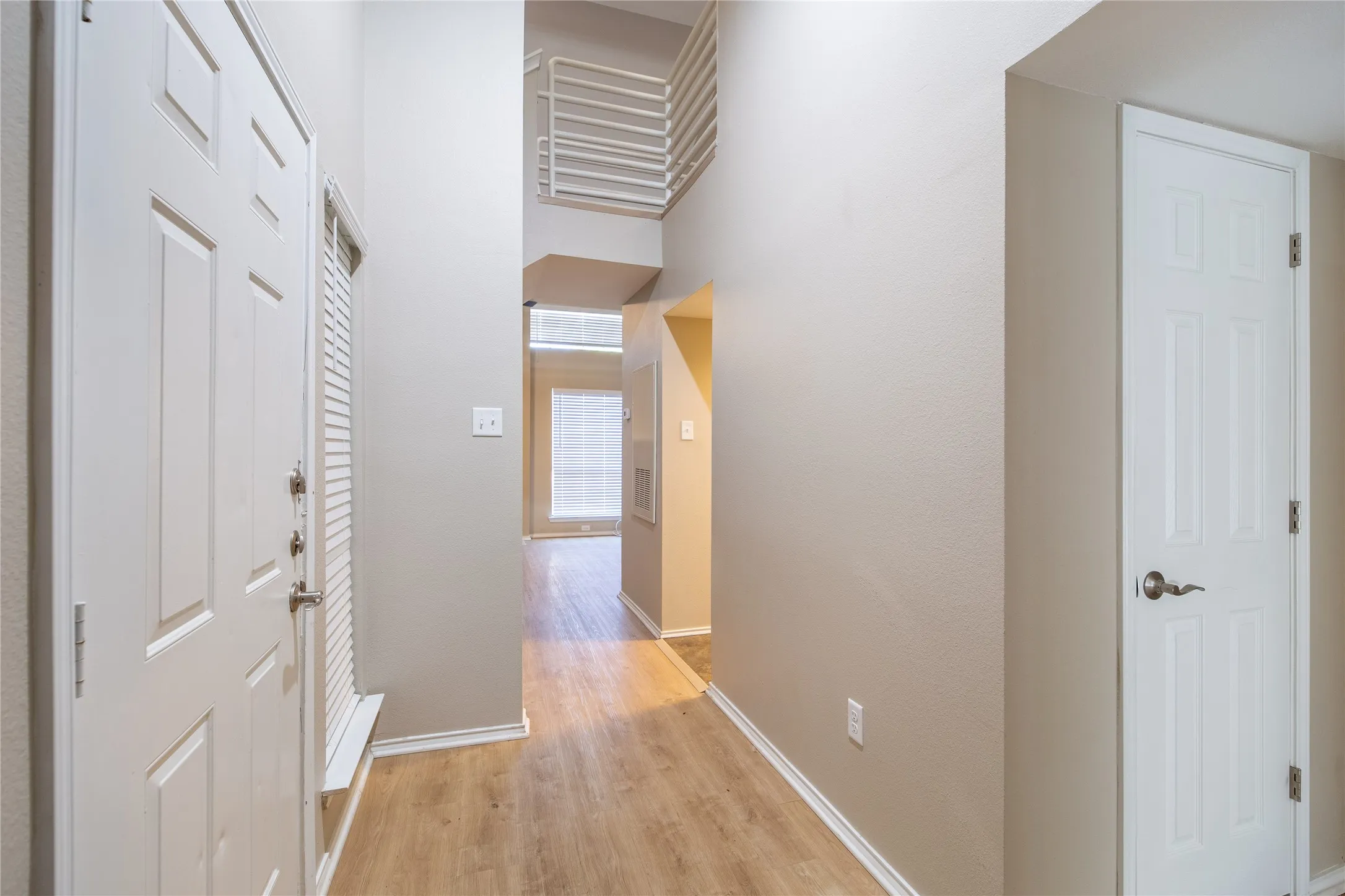 Double-height entry with wood-finish flooring and a contemporary metal railing