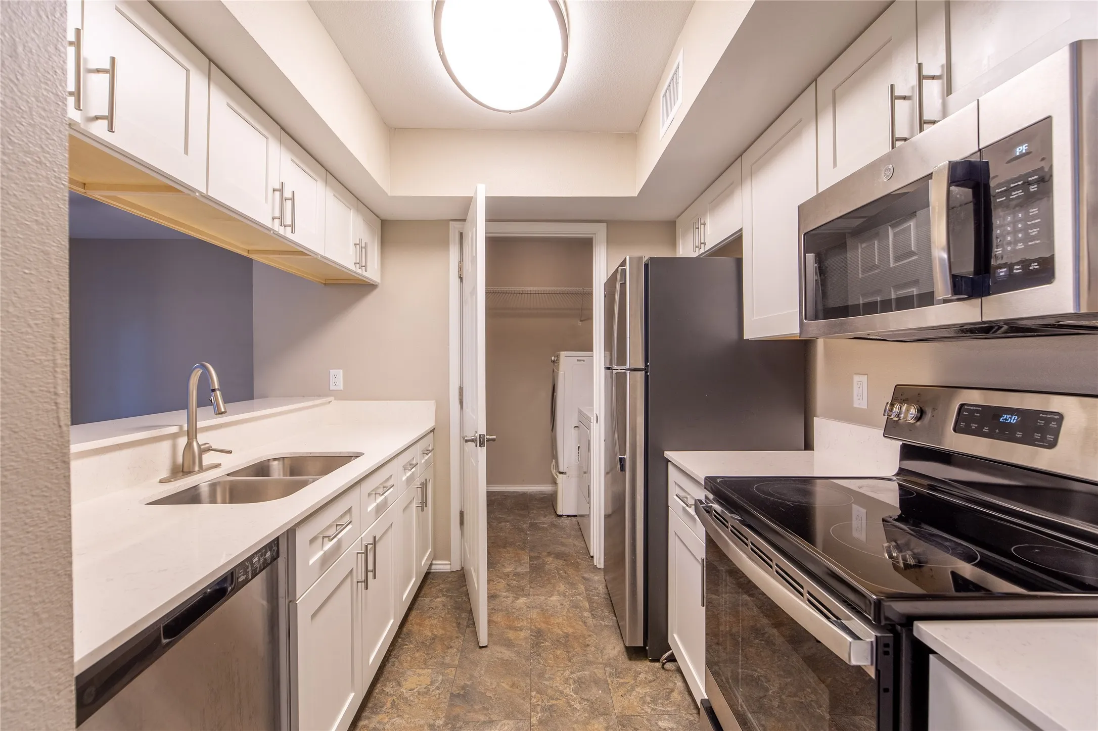 Kitchen featuring white shaker cabinetry, stainless steel appliances, light-toned countertops, and wood-finish flooring