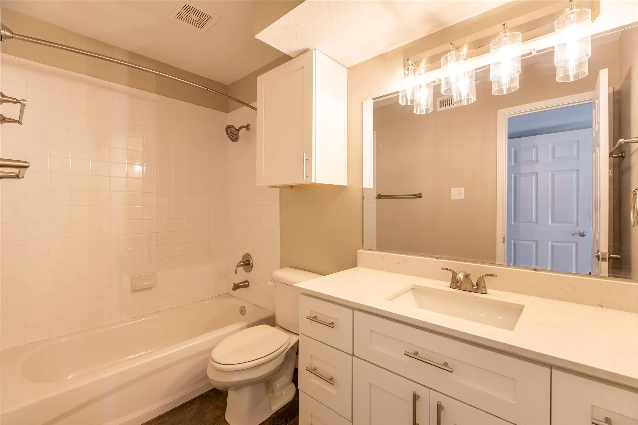 Bathroom featuring a white subway tile shower surround, a built-in bathtub, and a vanity with a light-colored countertop