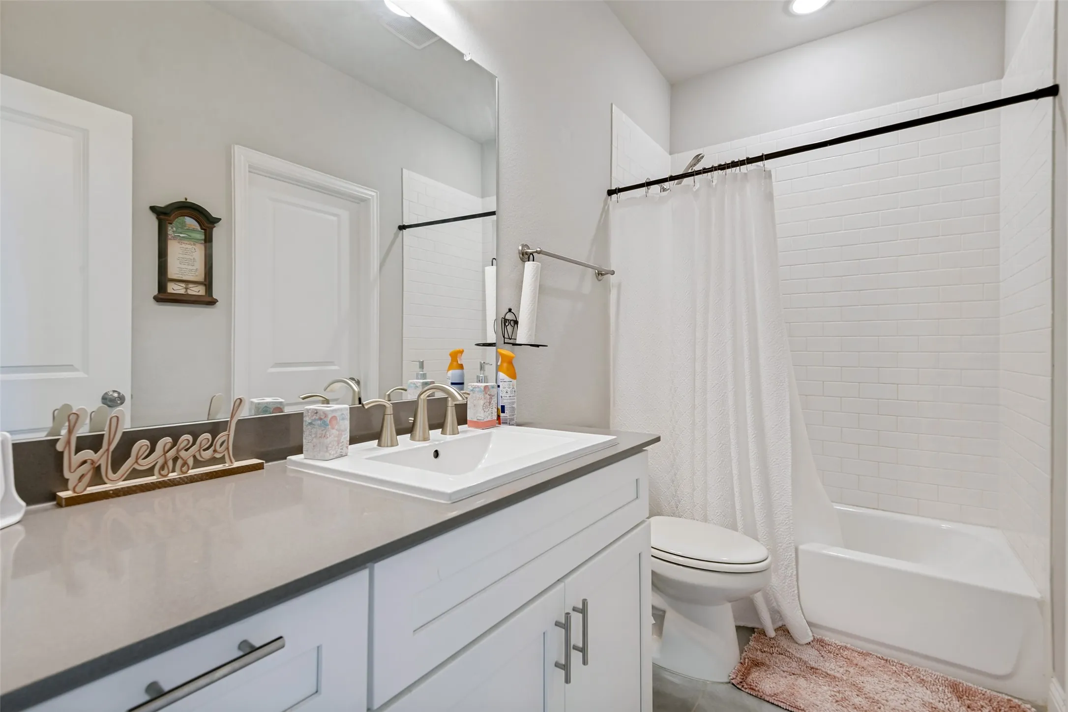White vanity with a rectangular undermount sink, brushed nickel faucet, and a large wall-mounted mirror