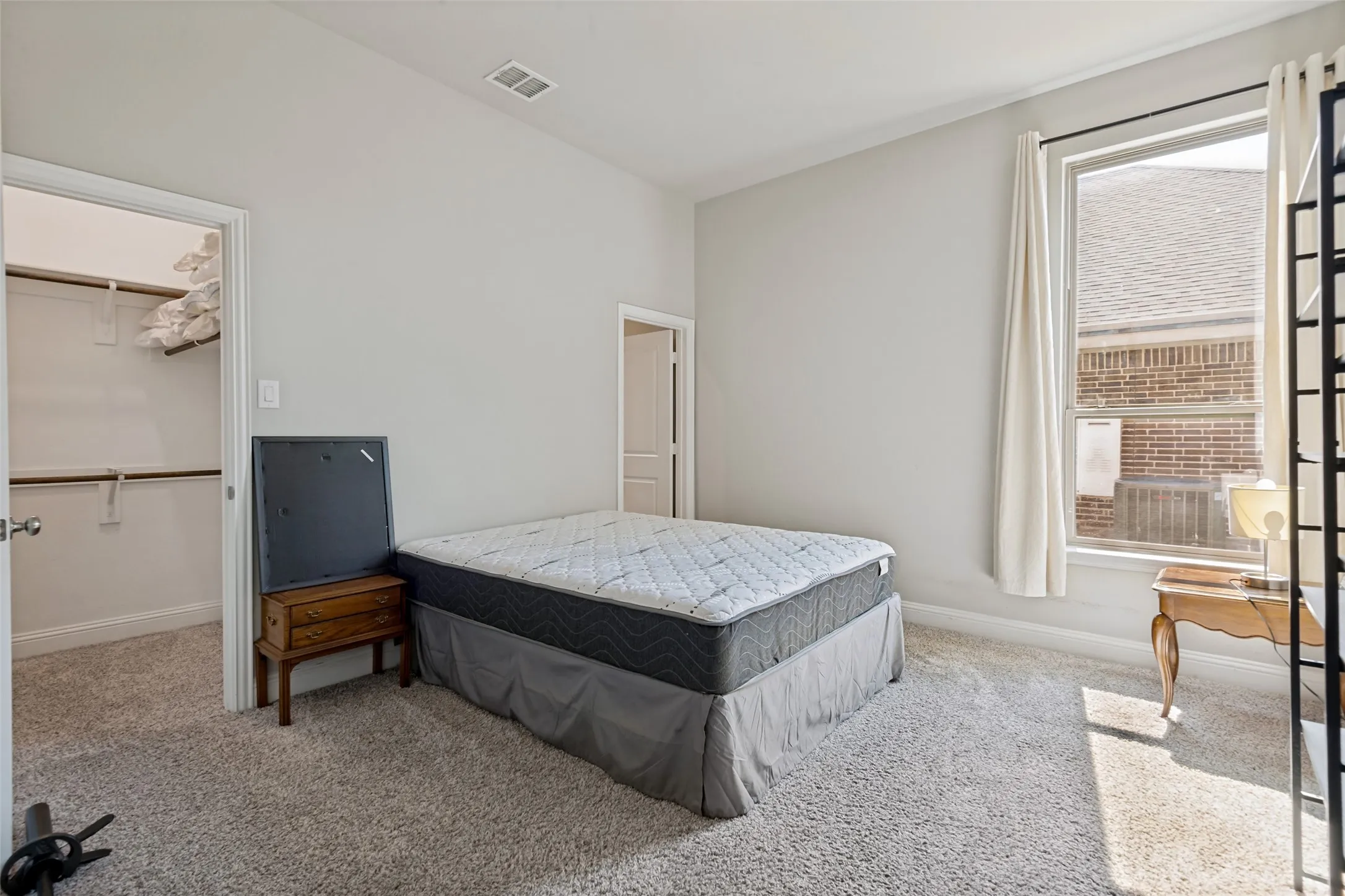 Neutral wall paint, plush carpet, single window with vertical blinds, recessed lighting, and a walk-in closet