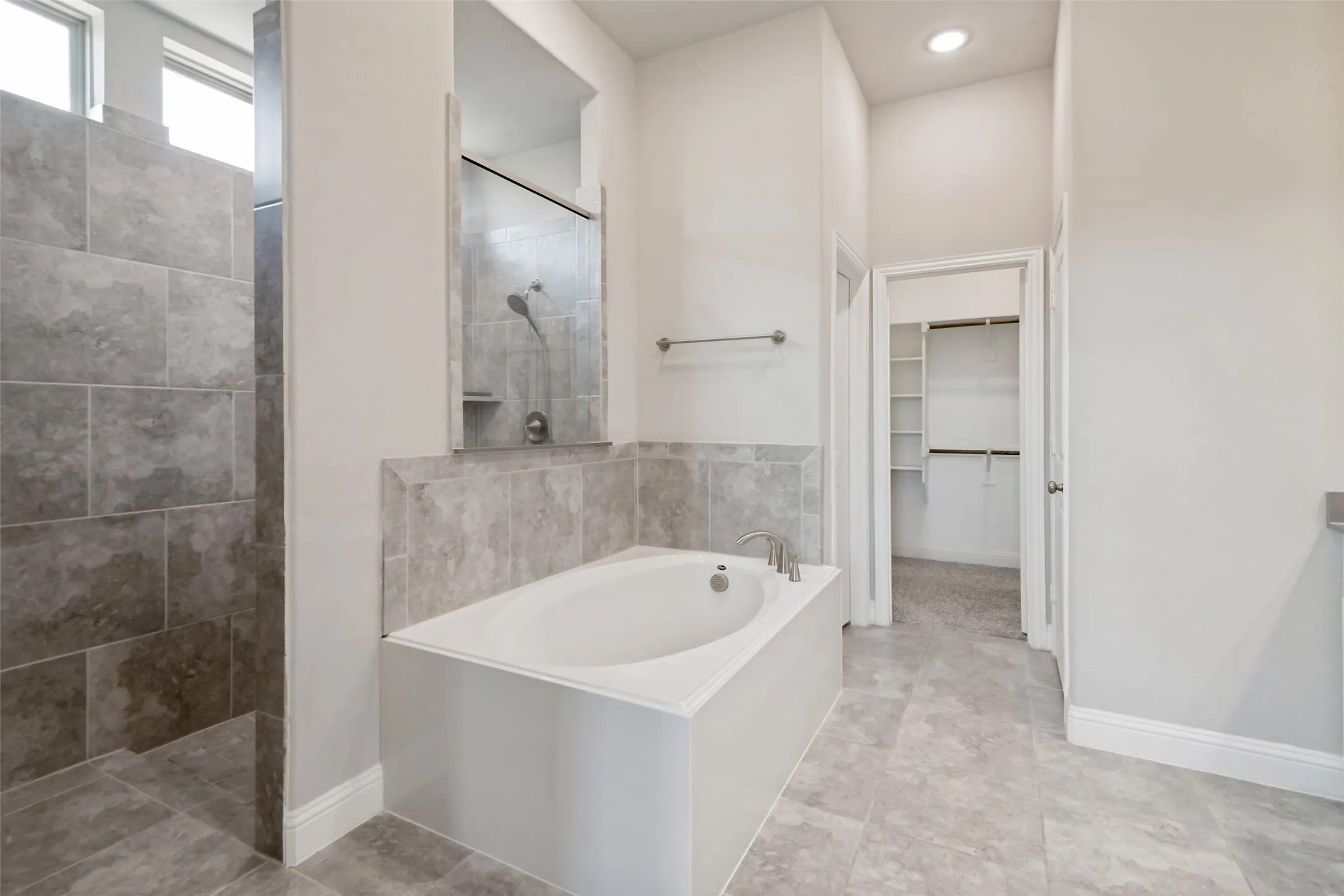 Enclosed shower with tiled walls, separate soaking tub with tiled surround, and tiled flooring