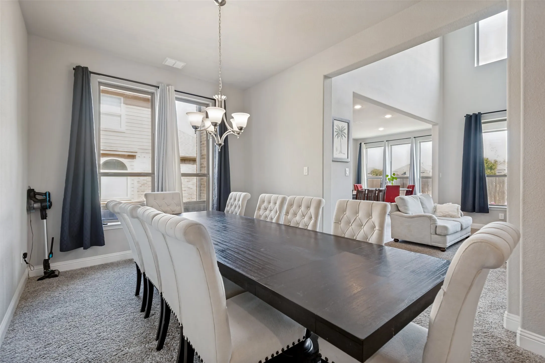Carpeted dining area with a multi-light chandelier and natural light from multiple windows