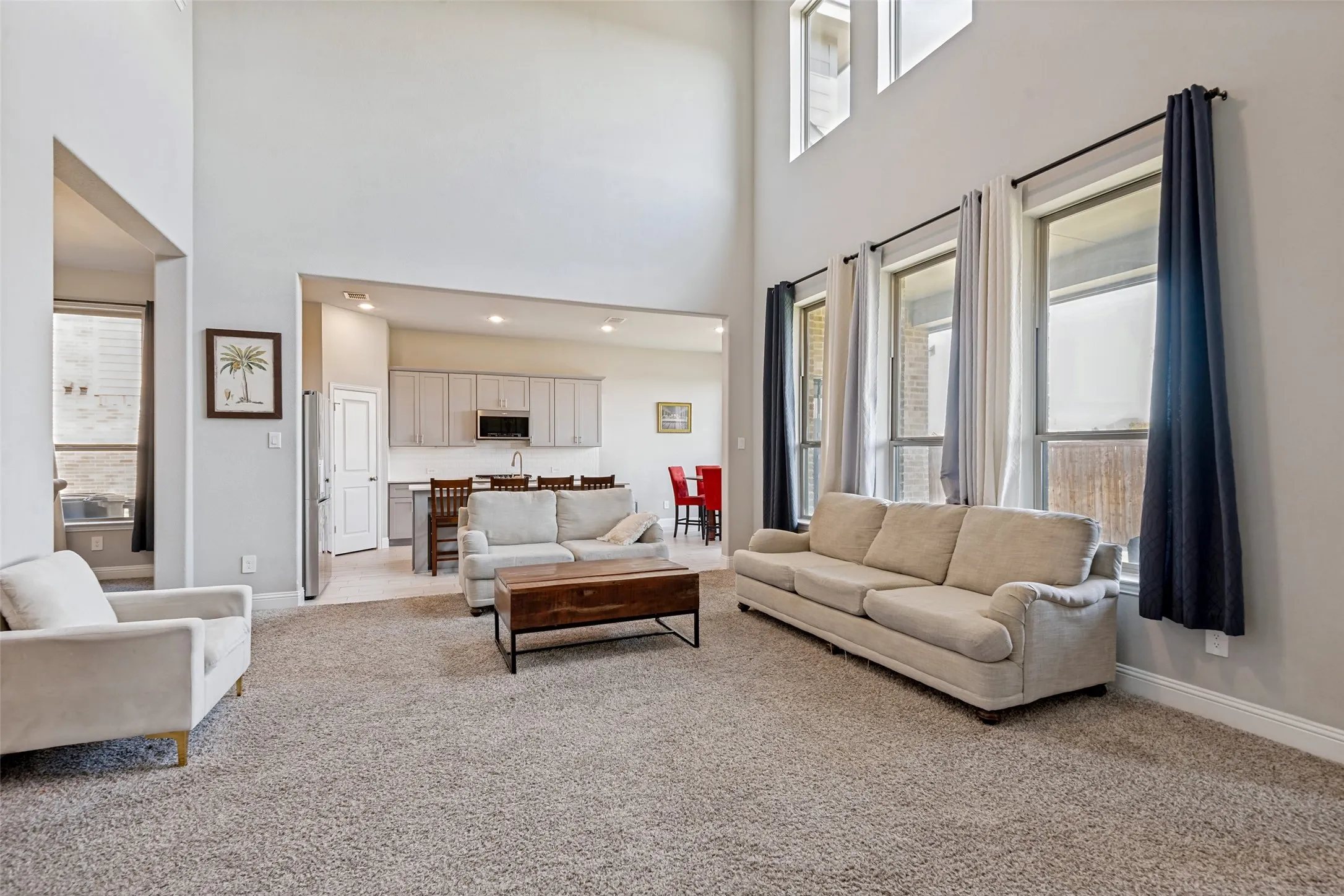 Great room with high ceilings, large windows, recessed lighting, and a neutral color palette
