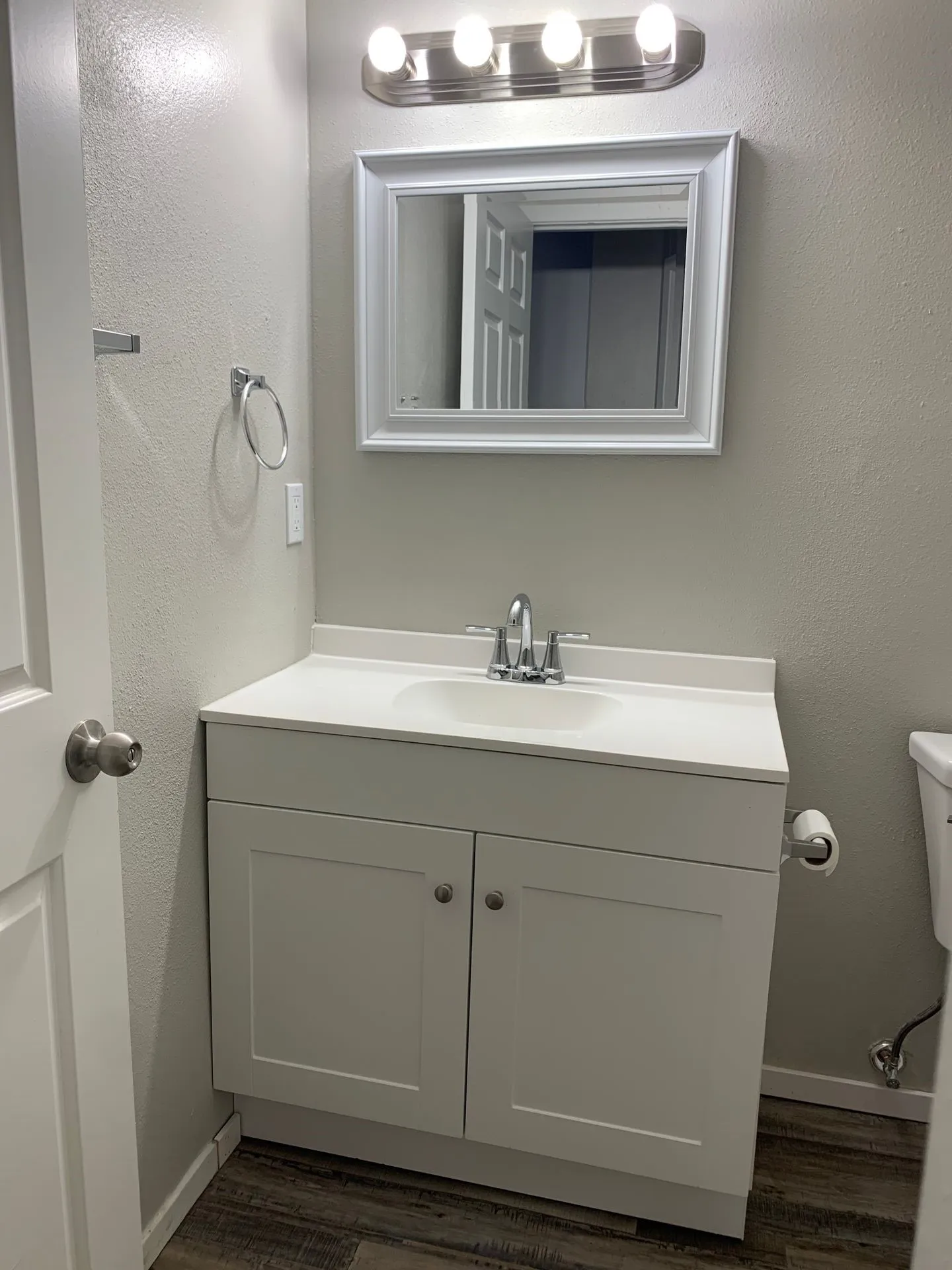 White shaker-style vanity with a single basin sink, chrome faucet, and white countertop